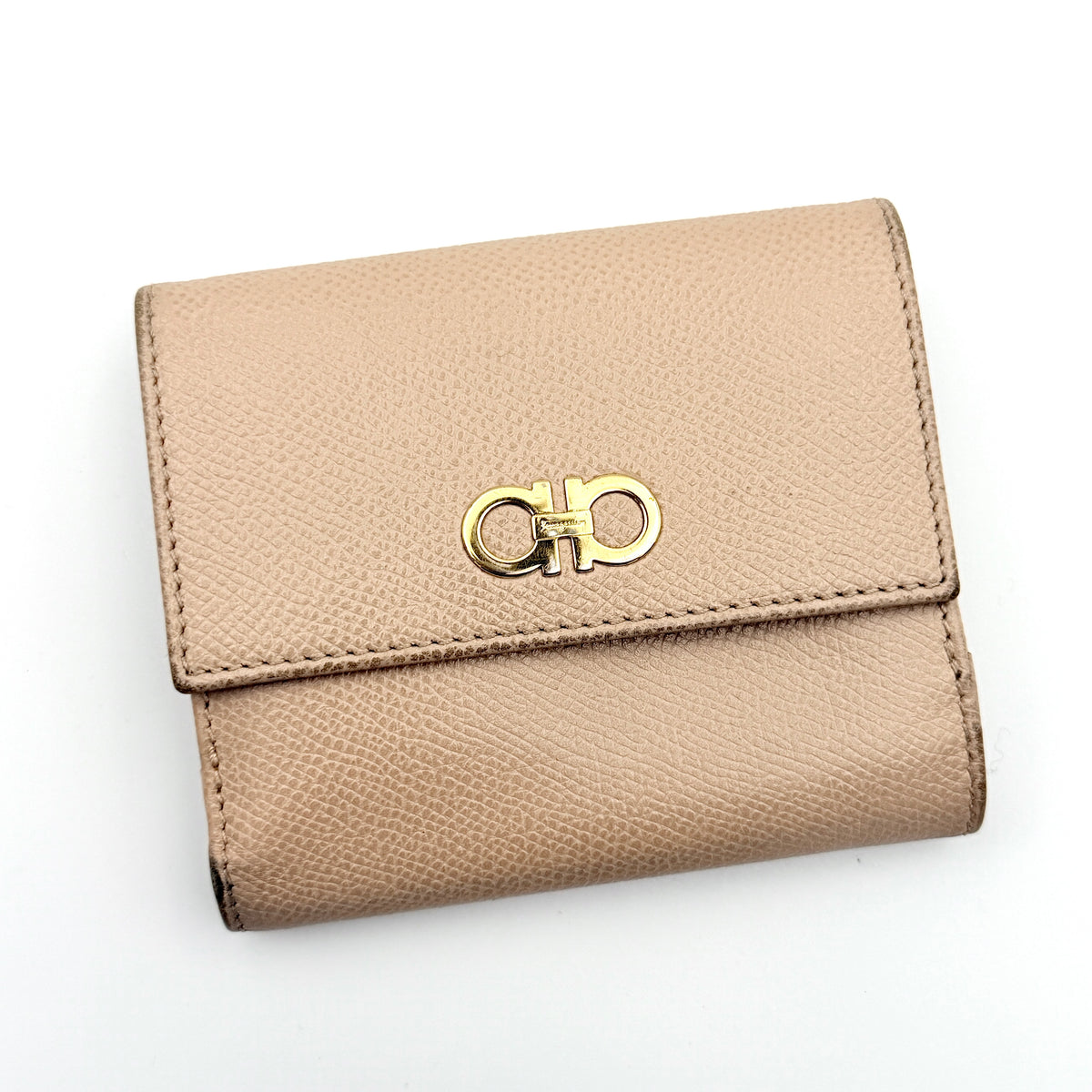 Salvatore Ferragamo beige grained leather compact bifold wallet with gold Gancini hardware, photographed on a white background.