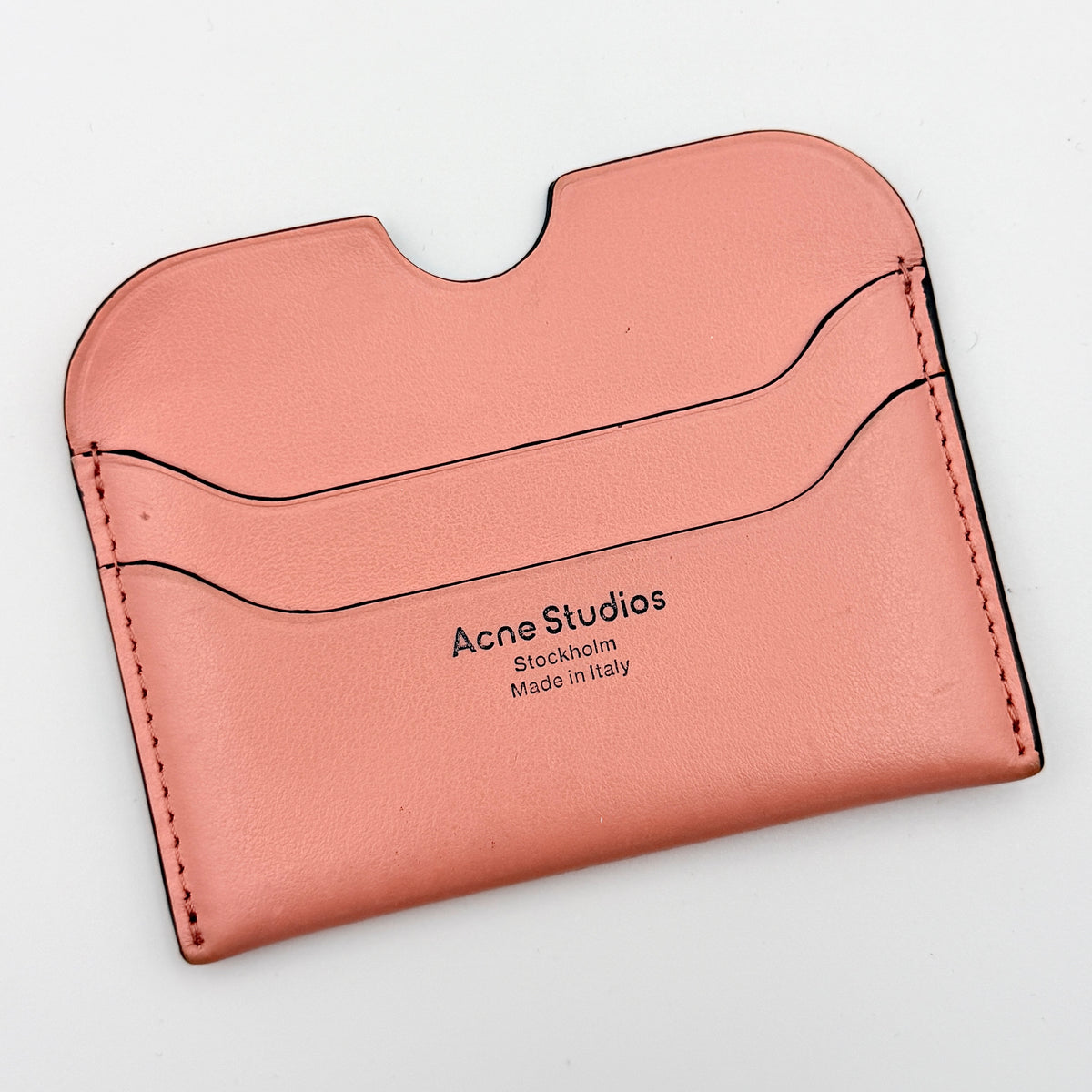 Acne Studios pink leather card holder with embossed logo and double card slots, shown against a clean white background.