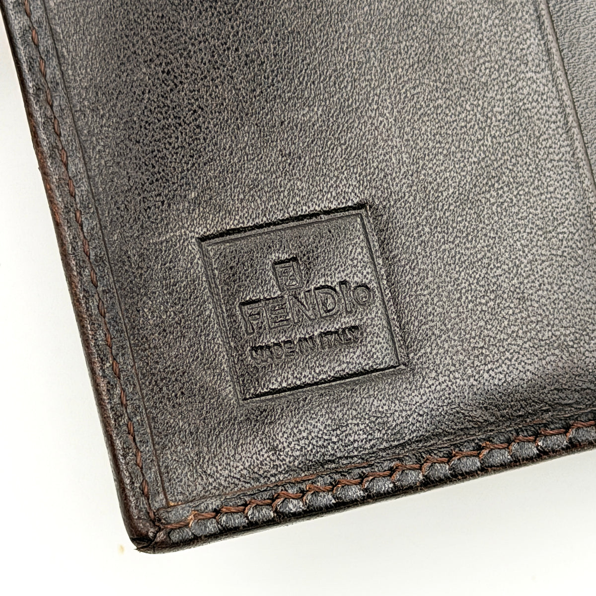 Fendi FF Zucca bifold wallet in brown and black canvas with leather trim, front snap tab detail.