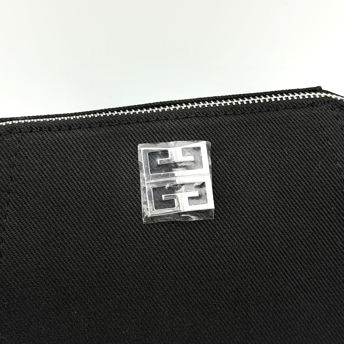 Givenchy black cosmetic pouch with silver-tone logo plaque and zip, photographed against a clean white background.