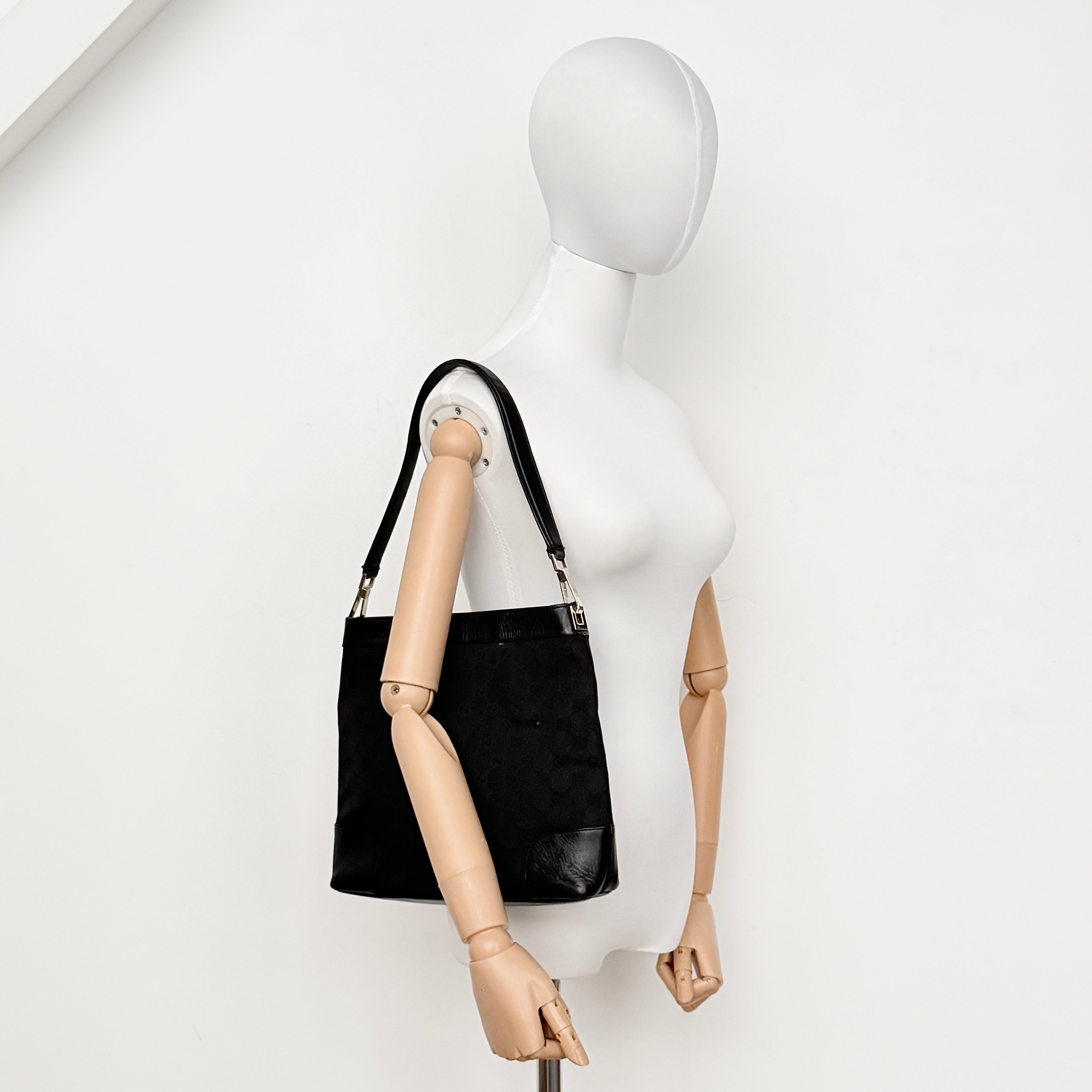 Gucci GG Monogram Bucket Shoulder Bag in black canvas and leather with silver-tone hardware, shown on a white background.