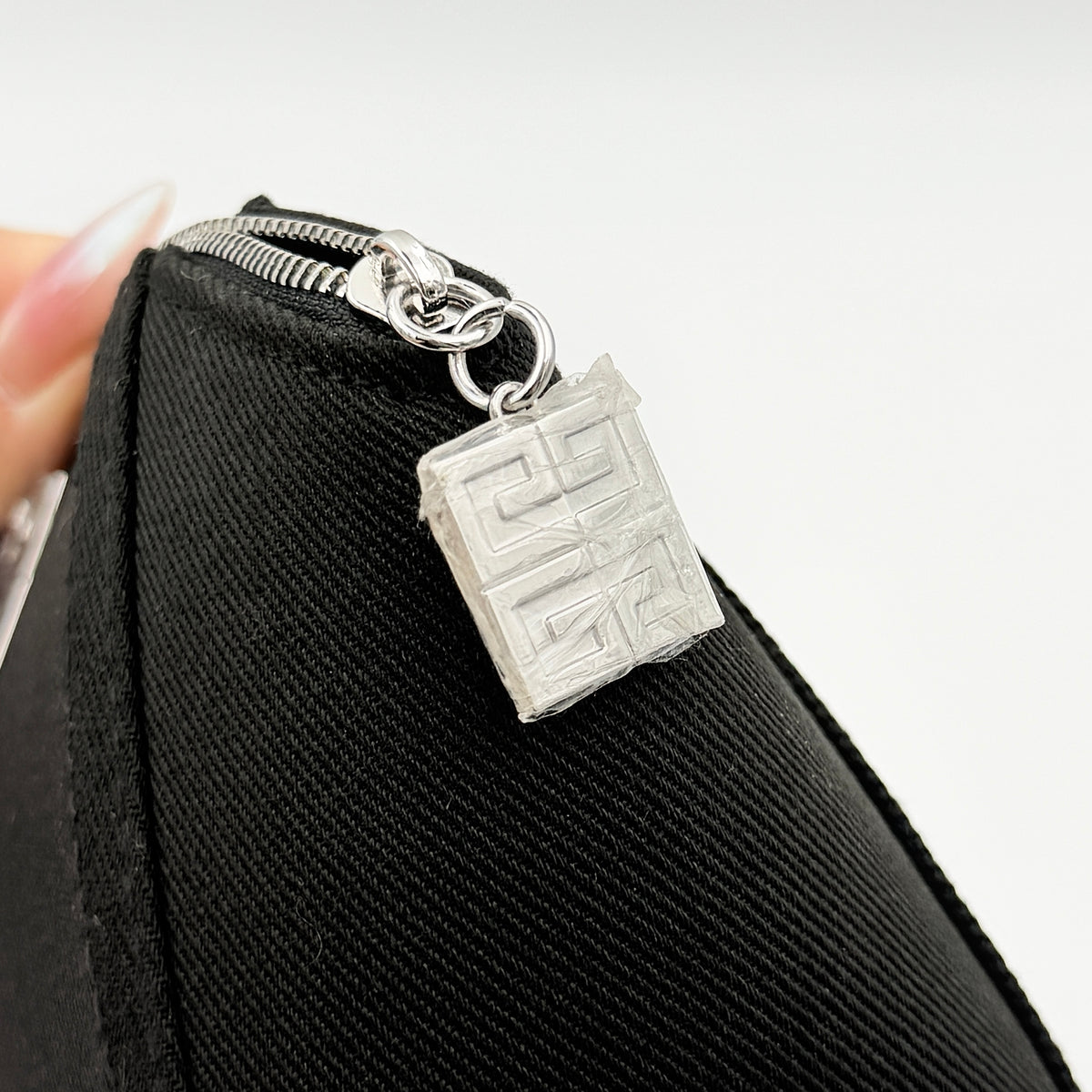 Givenchy black cosmetic pouch with silver-tone logo plaque and zip, photographed against a clean white background.