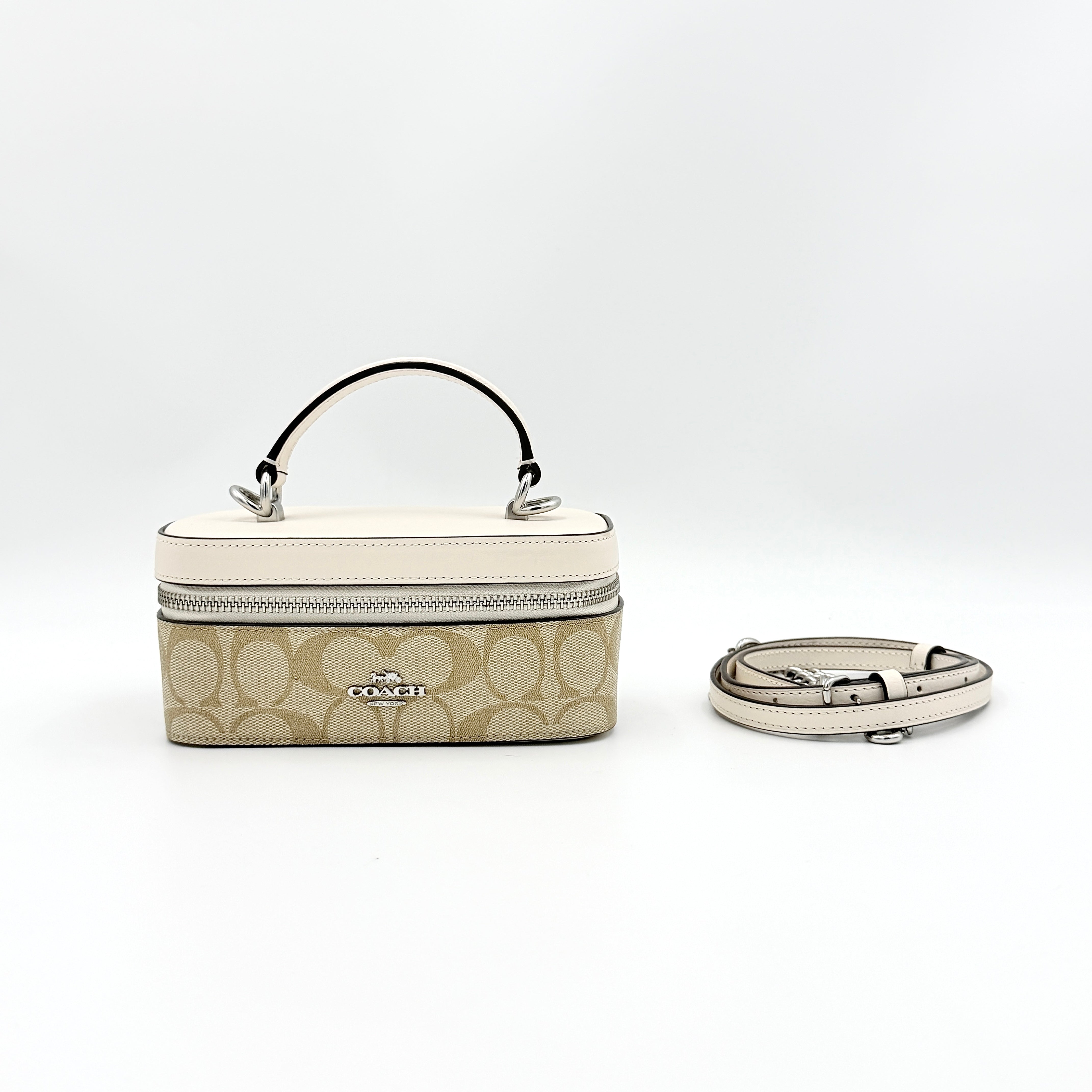 Coach 2Way Signature Train Case in beige and white canvas with a leather top handle and detachable strap, shown with silver zip hardware.