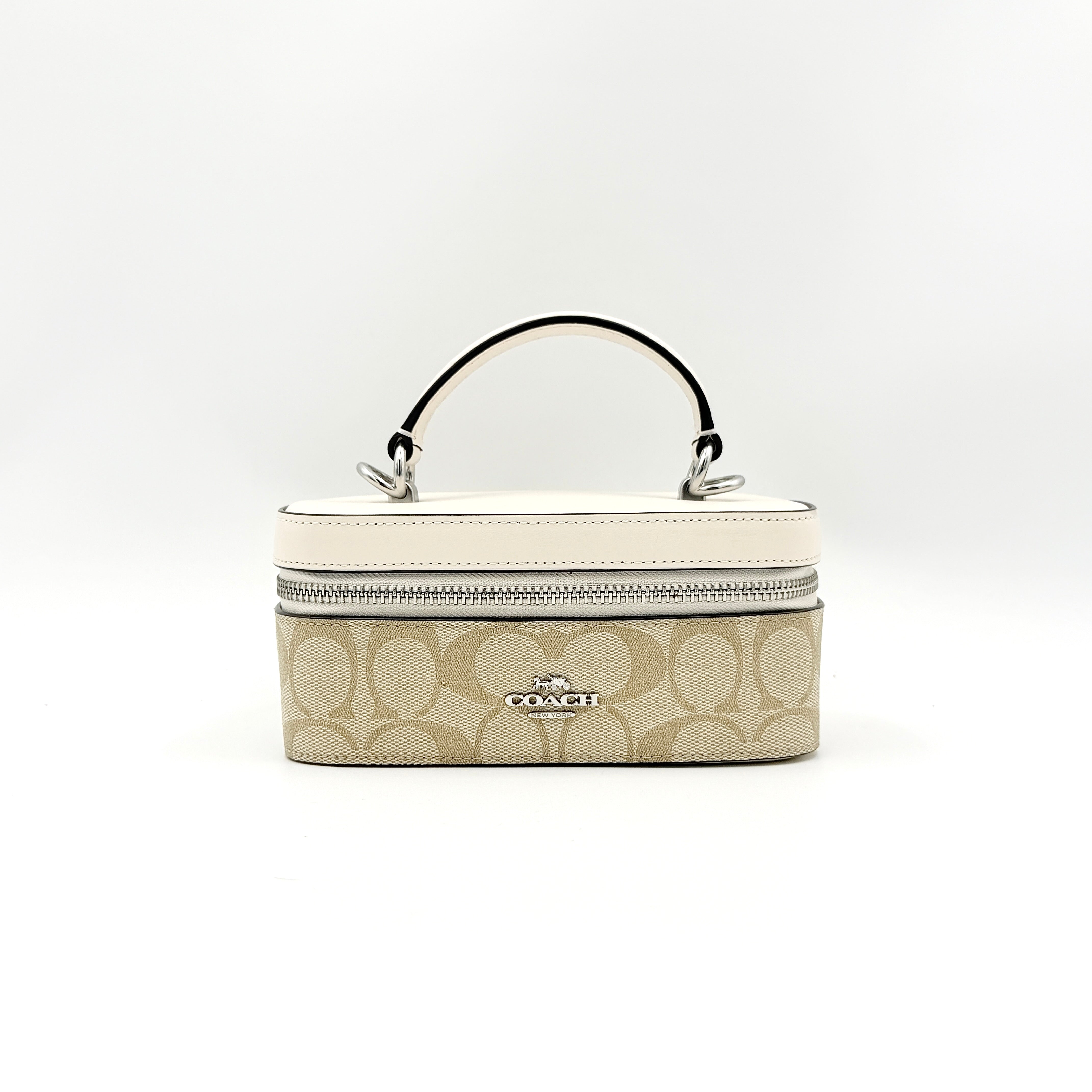 Coach 2Way Signature Train Case in beige and white canvas with a leather top handle and detachable strap, shown with silver zip hardware.