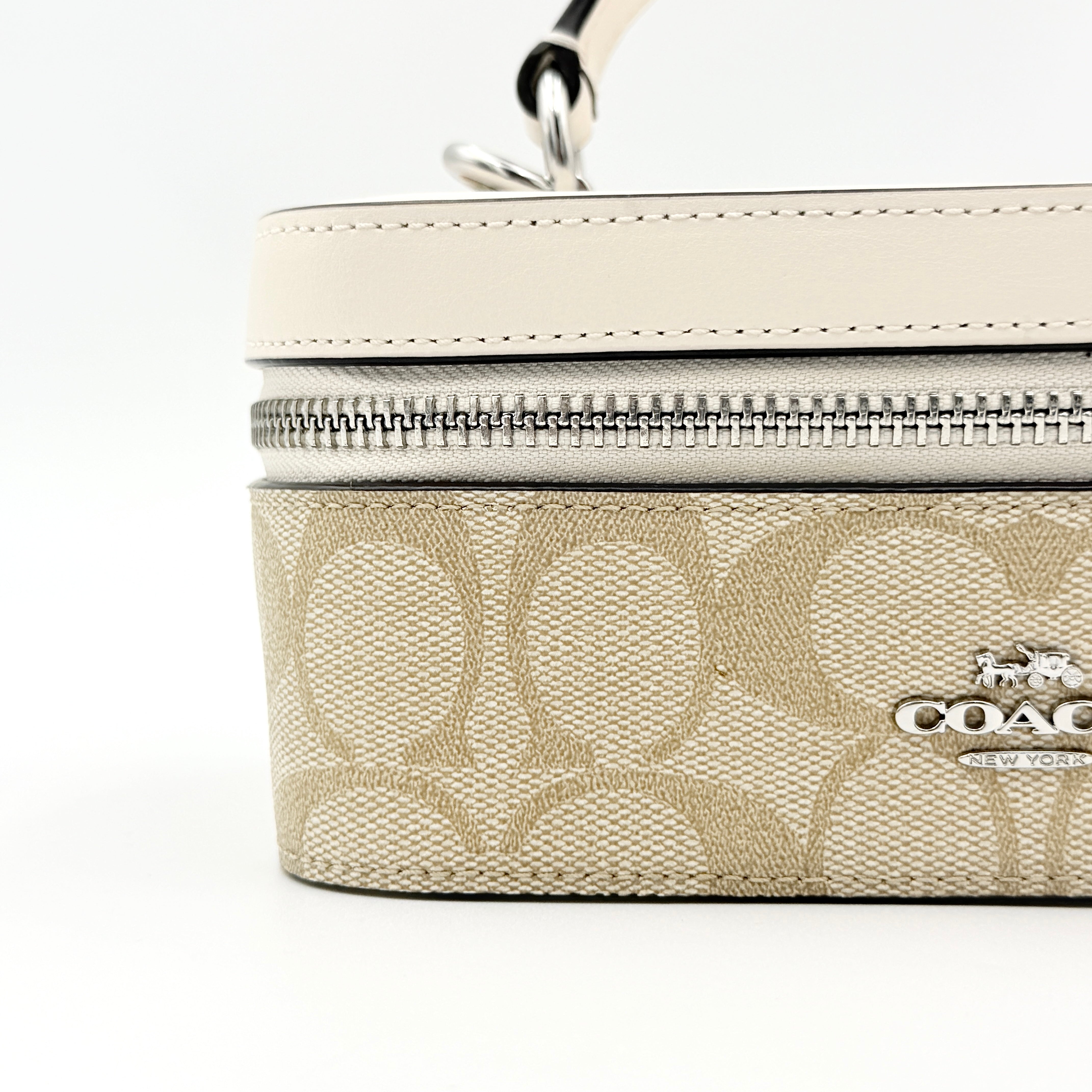 Coach 2Way Signature Train Case in beige and white canvas with a leather top handle and detachable strap, shown with silver zip hardware.