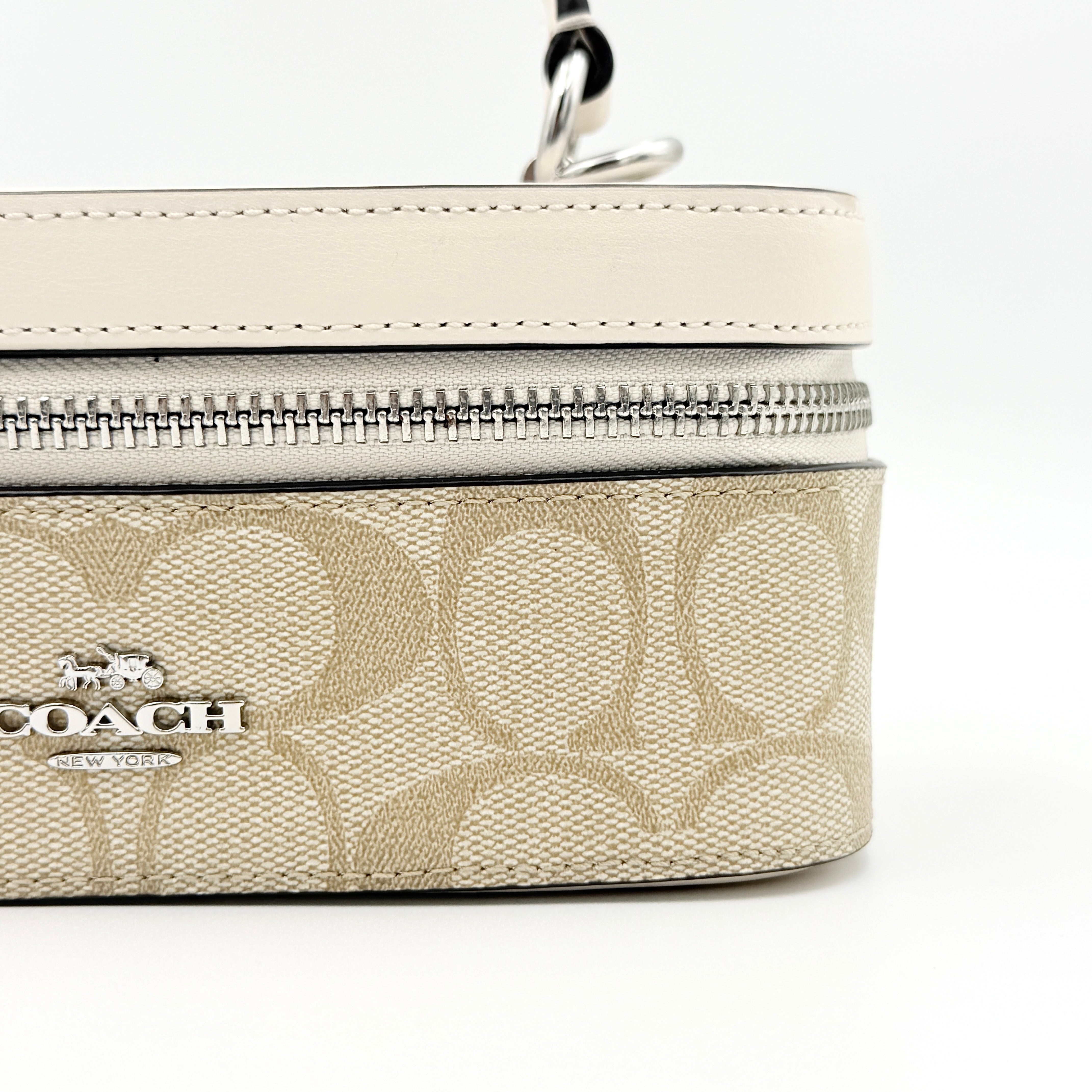 Coach 2Way Signature Train Case in beige and white canvas with a leather top handle and detachable strap, shown with silver zip hardware.