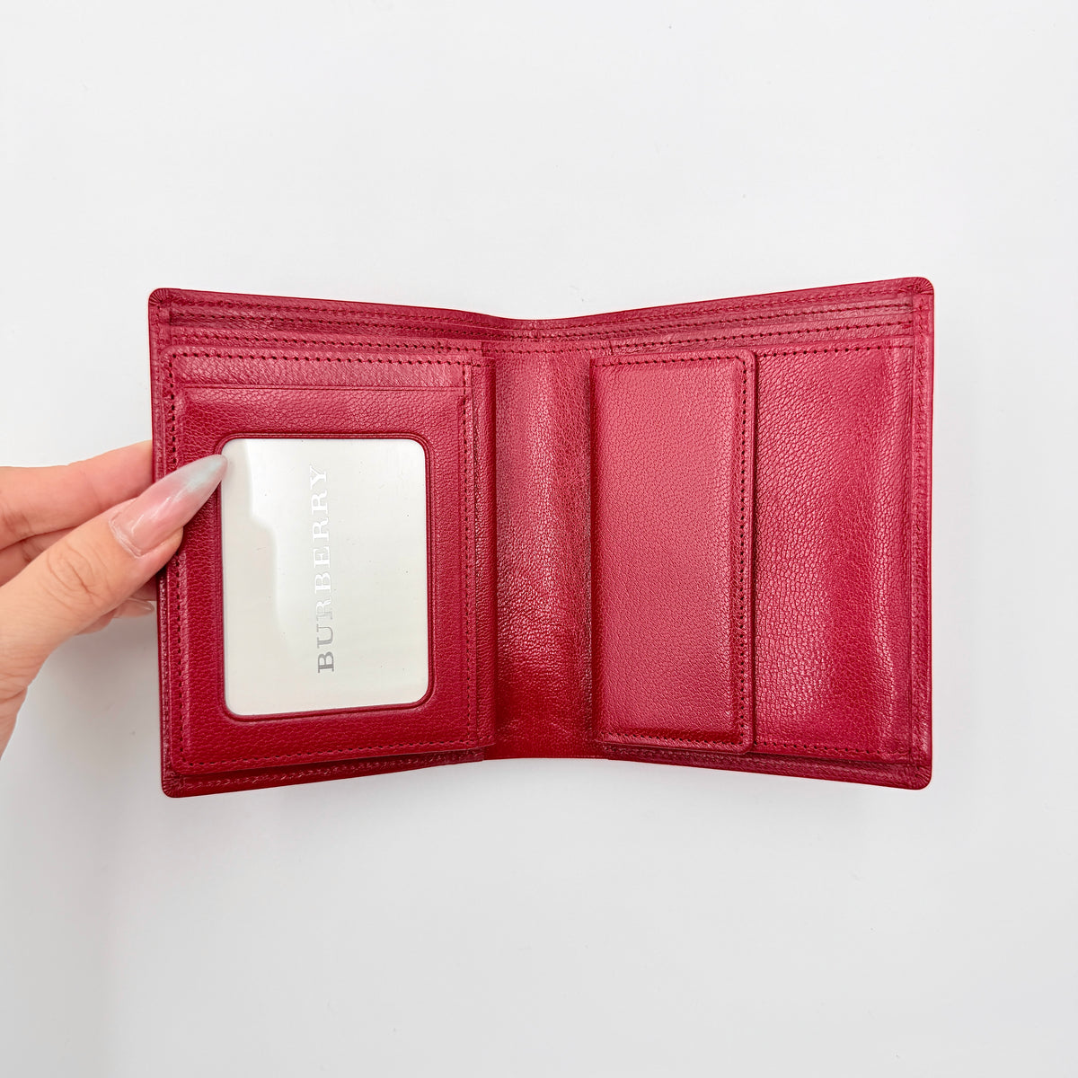 Burberry Nova Check bifold wallet in grained red leather with signature tartan interior, shown closed against a white background