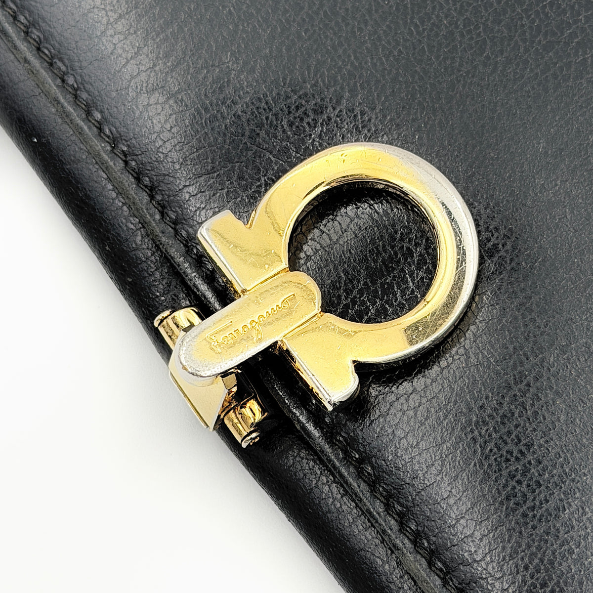 Salvatore Ferragamo Gancini Continental Wallet in black leather with gold-tone Gancini clasp, photographed closed on a white background.