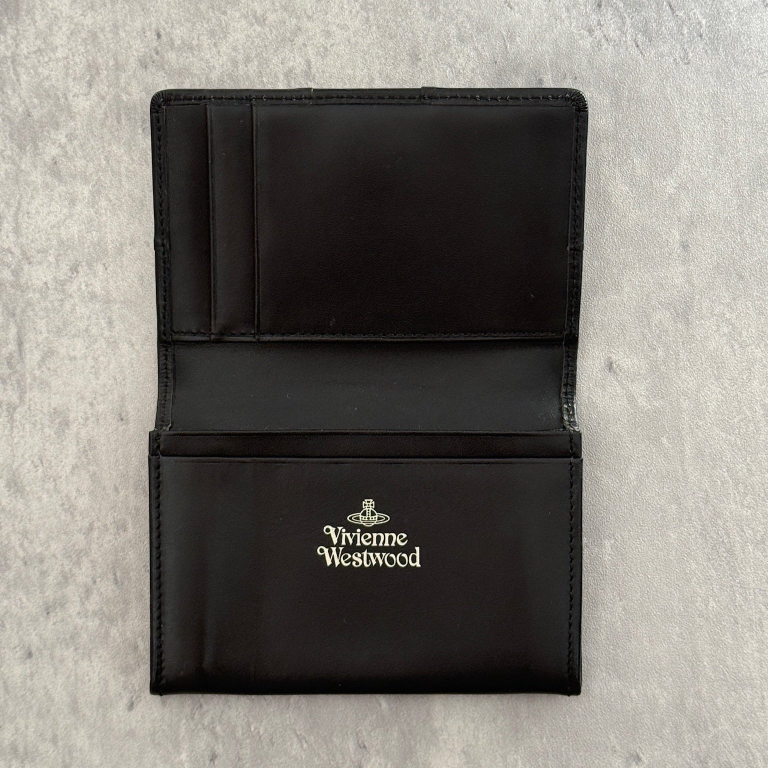 Black Vivienne Westwood cardholder with iconic silver Orb emblem, featuring multiple card slots and a central compartment, perfect for stylish organization.