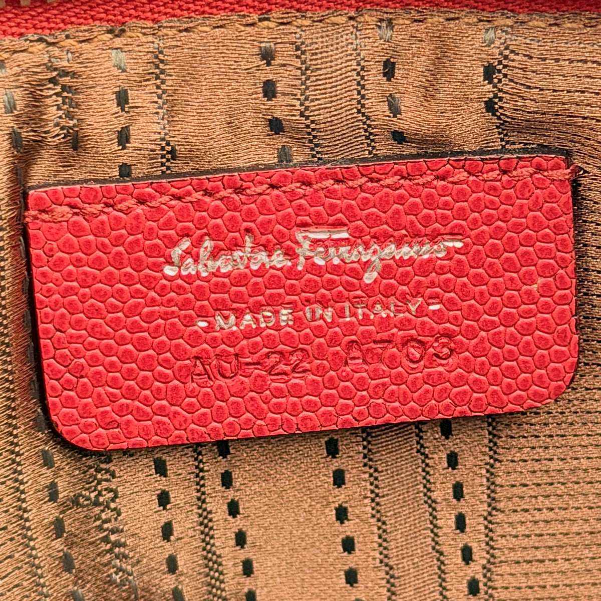 Salvatore Ferragamo red embossed leather wristlet with Gancini motif and wrist strap, shown against a white background.