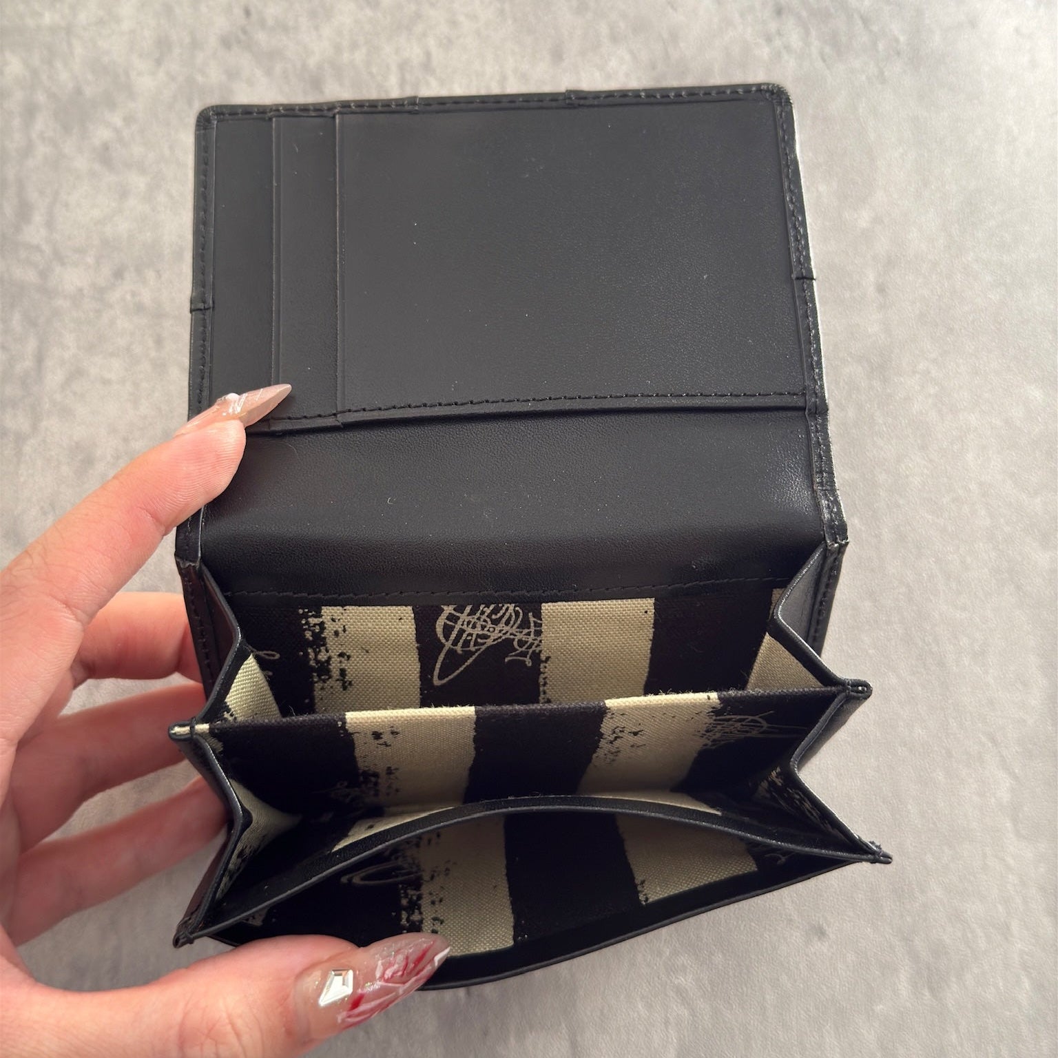 Black Vivienne Westwood cardholder with iconic silver Orb emblem, featuring multiple card slots and a central compartment, perfect for stylish organization.