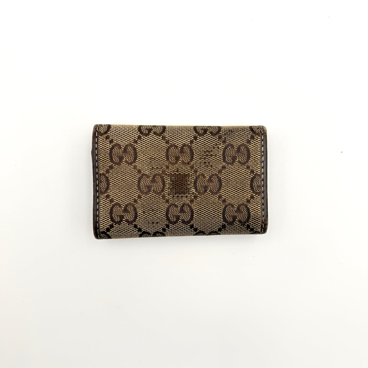 Gucci GG monogram canvas key case in brown with leather trim and a silver GG emblem on the front.