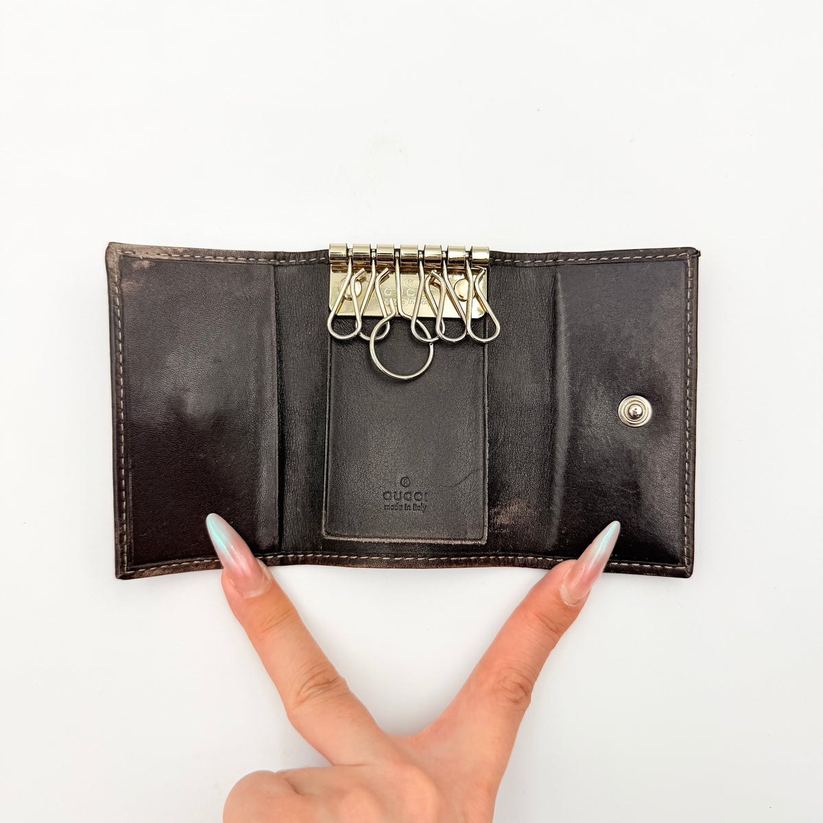 Gucci GG monogram canvas key case in brown with leather trim and a silver GG emblem on the front.