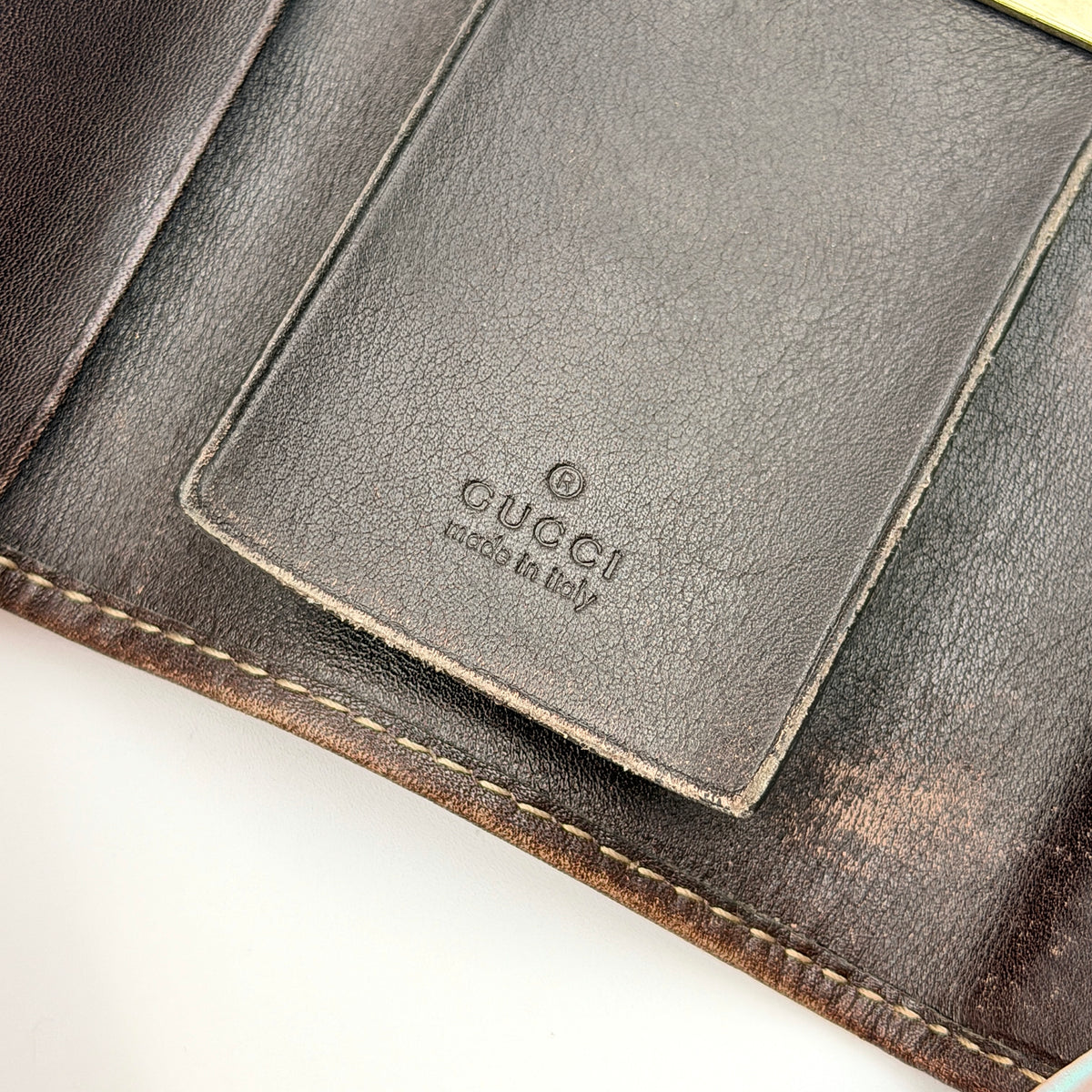 Gucci GG monogram canvas key case in brown with leather trim and a silver GG emblem on the front.
