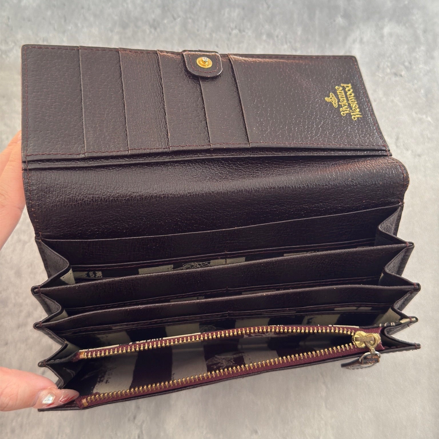 Vivienne Westwood Signature Orb Bi-fold Long Wallet in Black Leather with Gold-Tone Hardware and Multiple Interior Compartments.