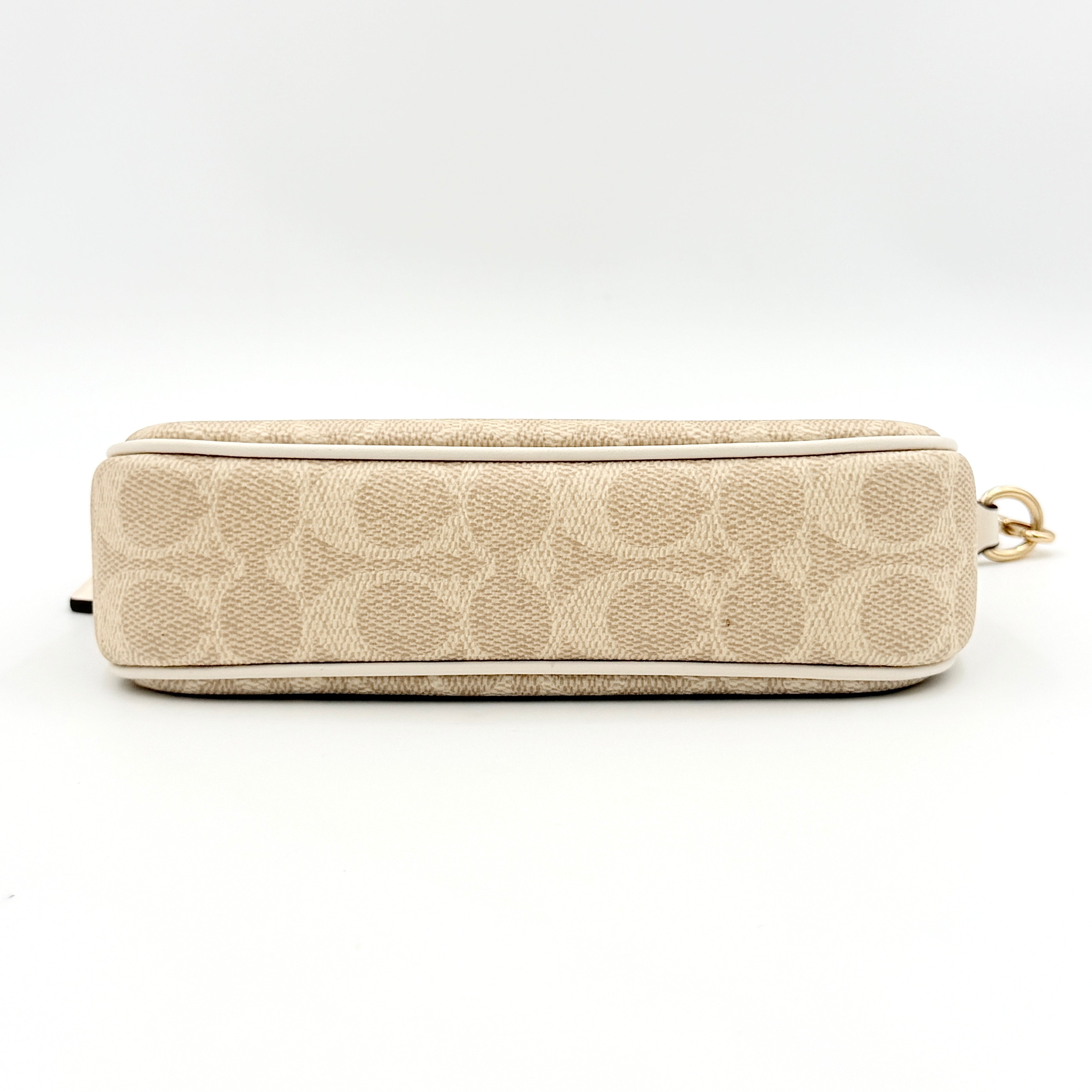 Coach Signature Nolita 19 Shoulder Bag in beige and white canvas with gold-tone hardware and detachable strap, photographed against a plain backdrop.
