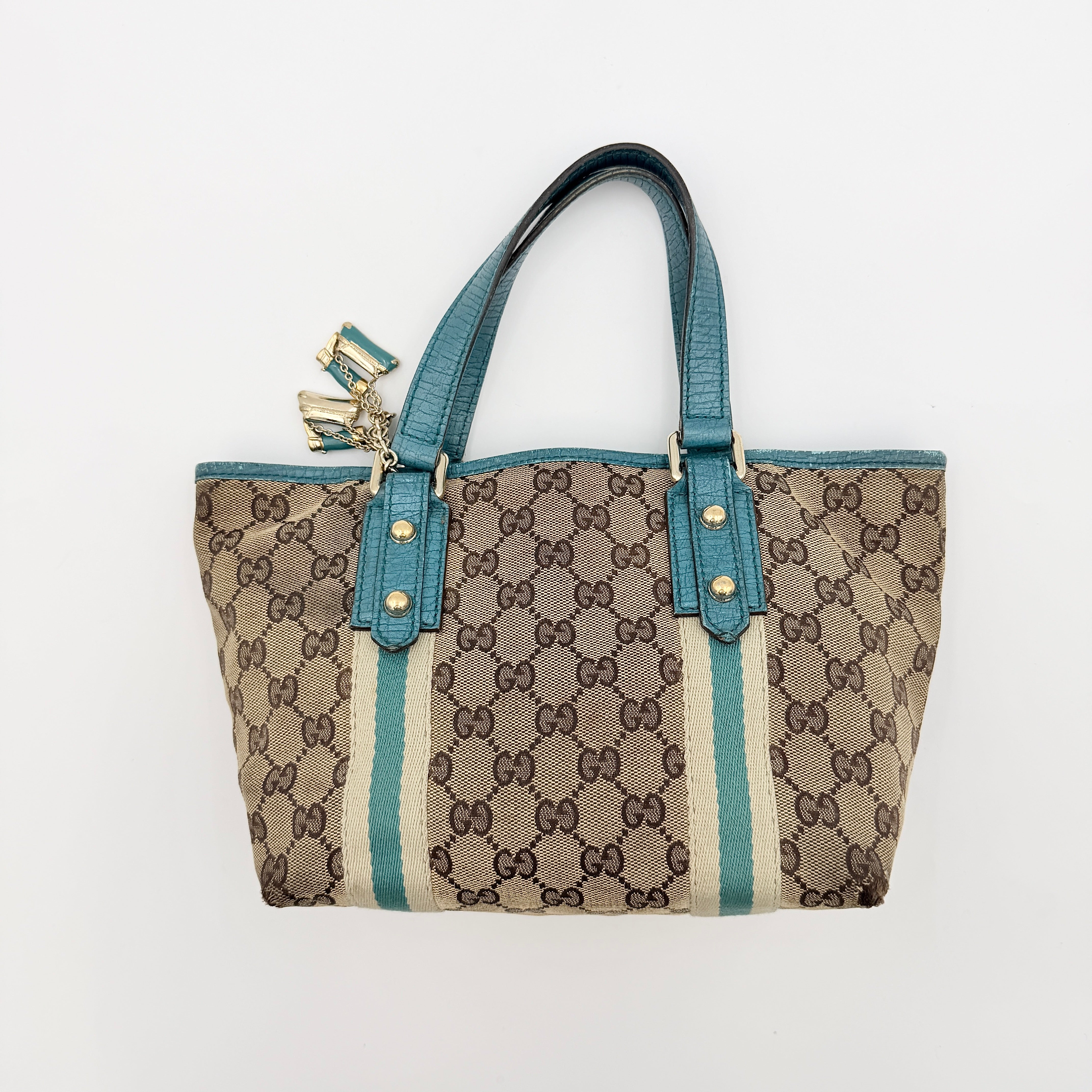 Gucci GG Monogram Jolicoeur Mini Shoulder Bag in beige canvas with teal blue leather trim and gold hardware, shown with a playful charm.