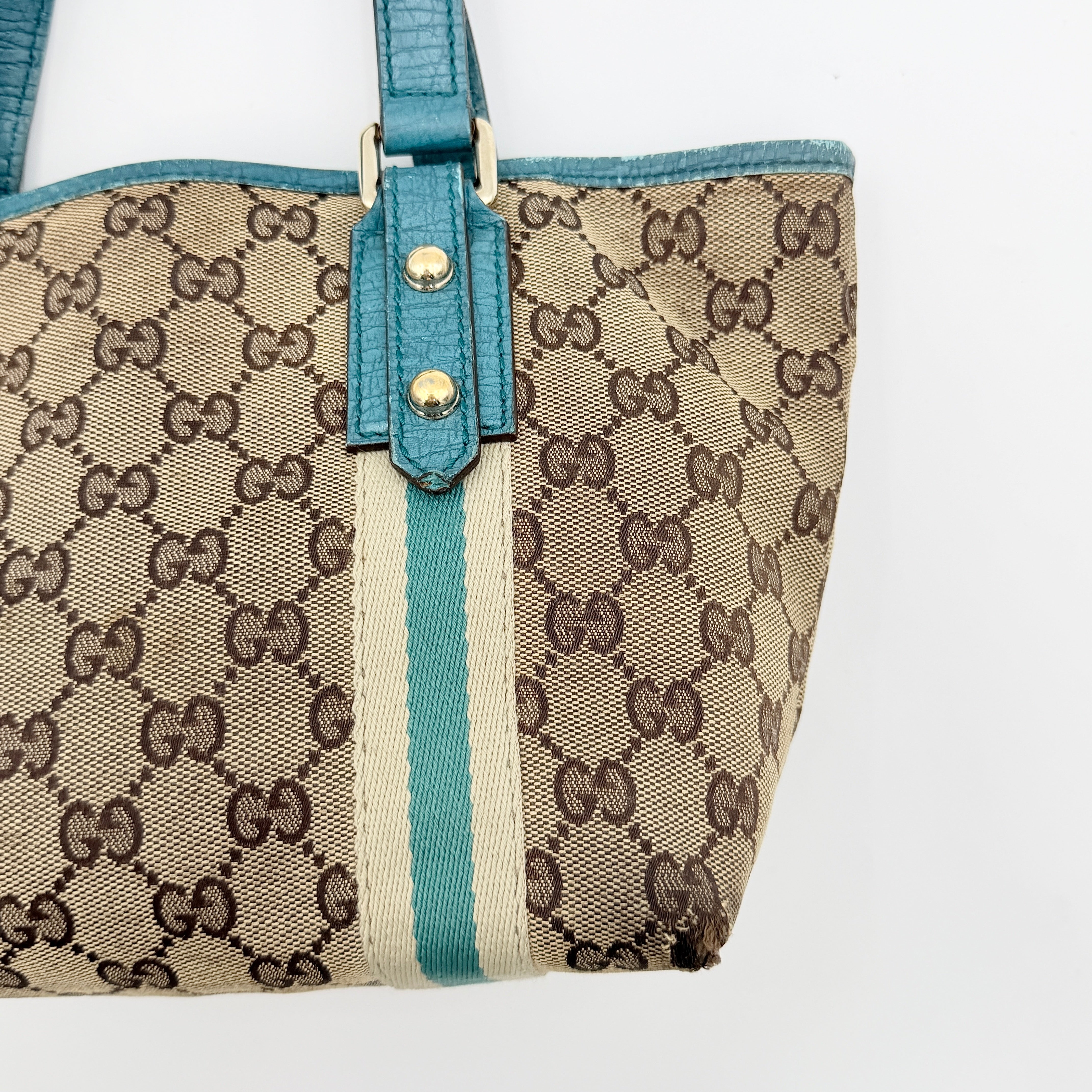 Gucci GG Monogram Jolicoeur Mini Shoulder Bag in beige canvas with teal blue leather trim and gold hardware, shown with a playful charm.