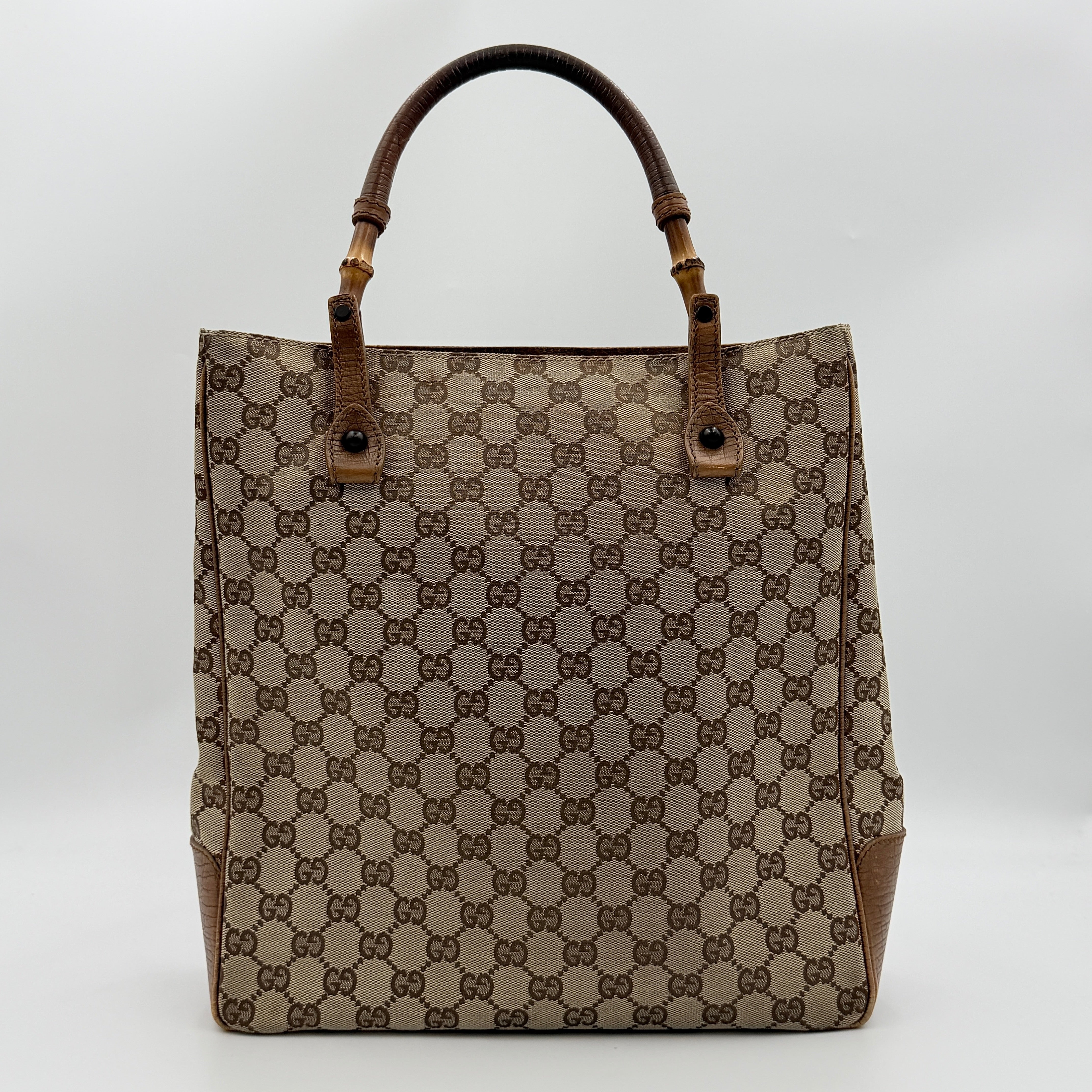 Gucci GG Monogram Bamboo Shoulder Bag in beige and brown canvas with bamboo top handles displayed upright.