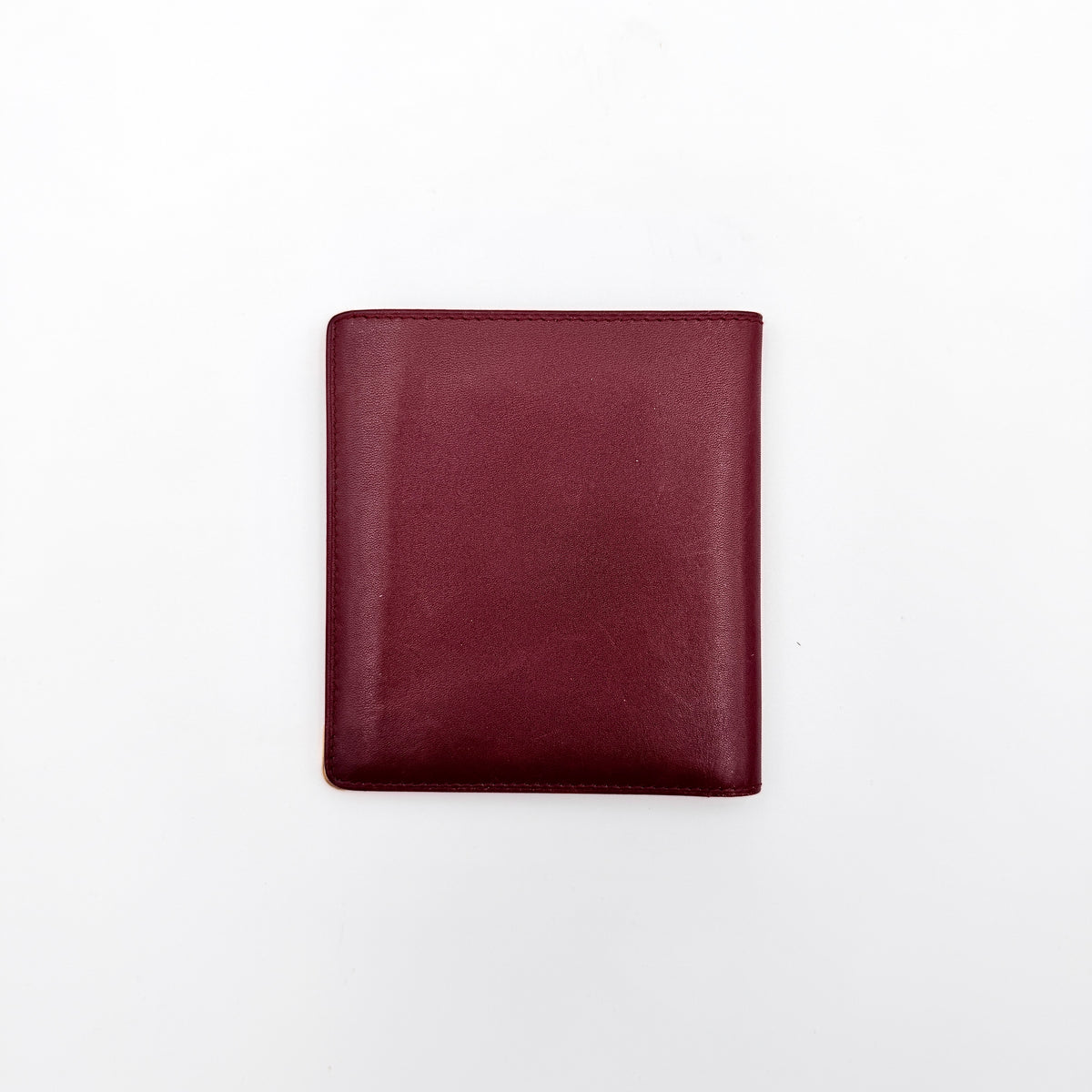 Cartier Must de Cartier bifold wallet in burgundy leather with gold-tone corner hardware and embossed logo, shown with authenticity card.