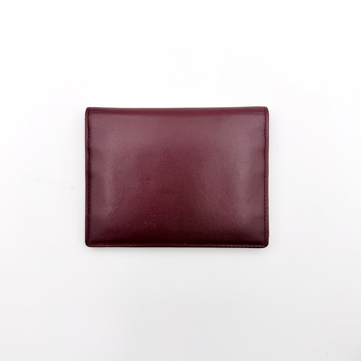 Cartier Must de Cartier card case in rich burgundy leather with gold-tone corner details and an embossed logo.