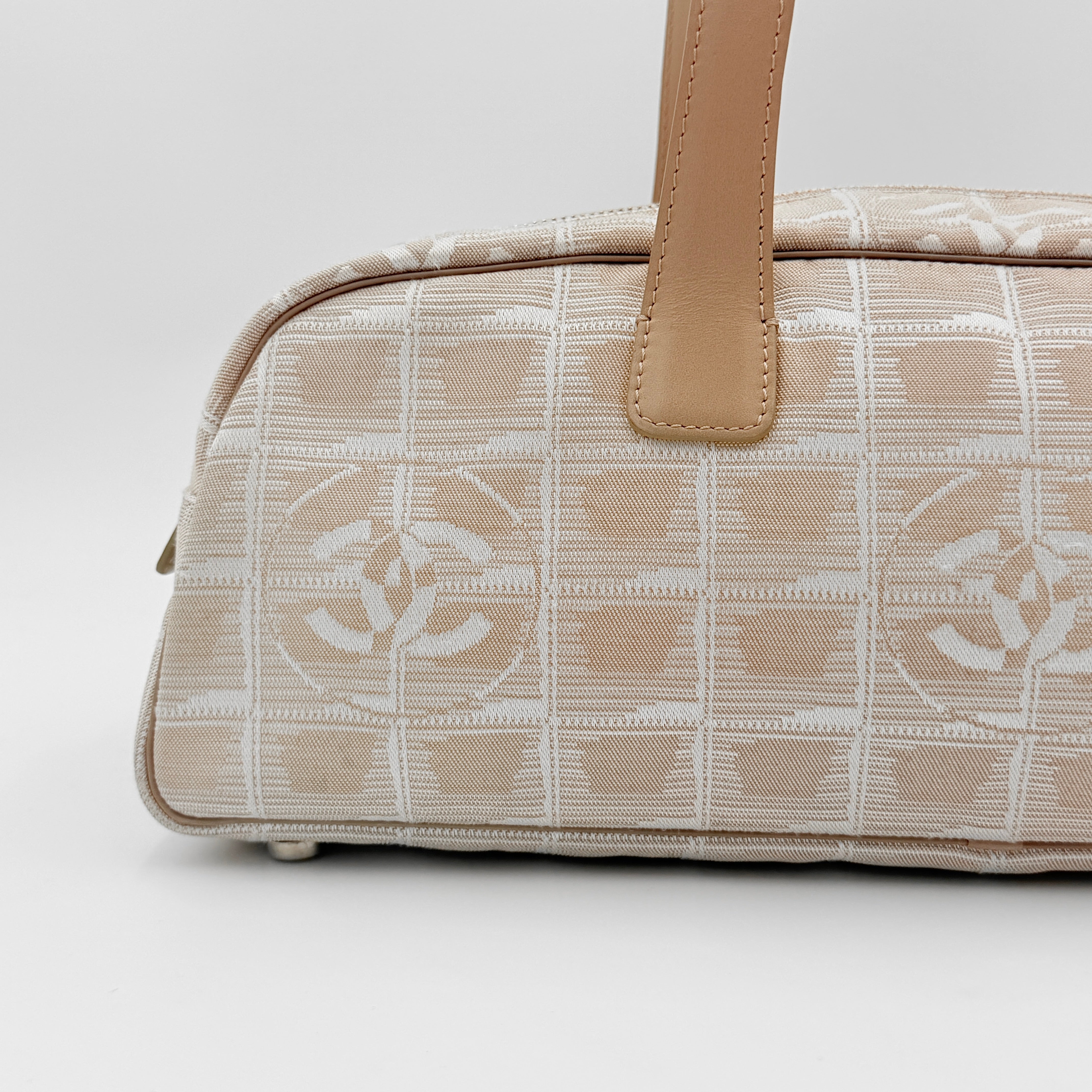 Chanel Travel Mini Boston Bag in beige nylon with CC motif and tan leather handles, shown in front view.