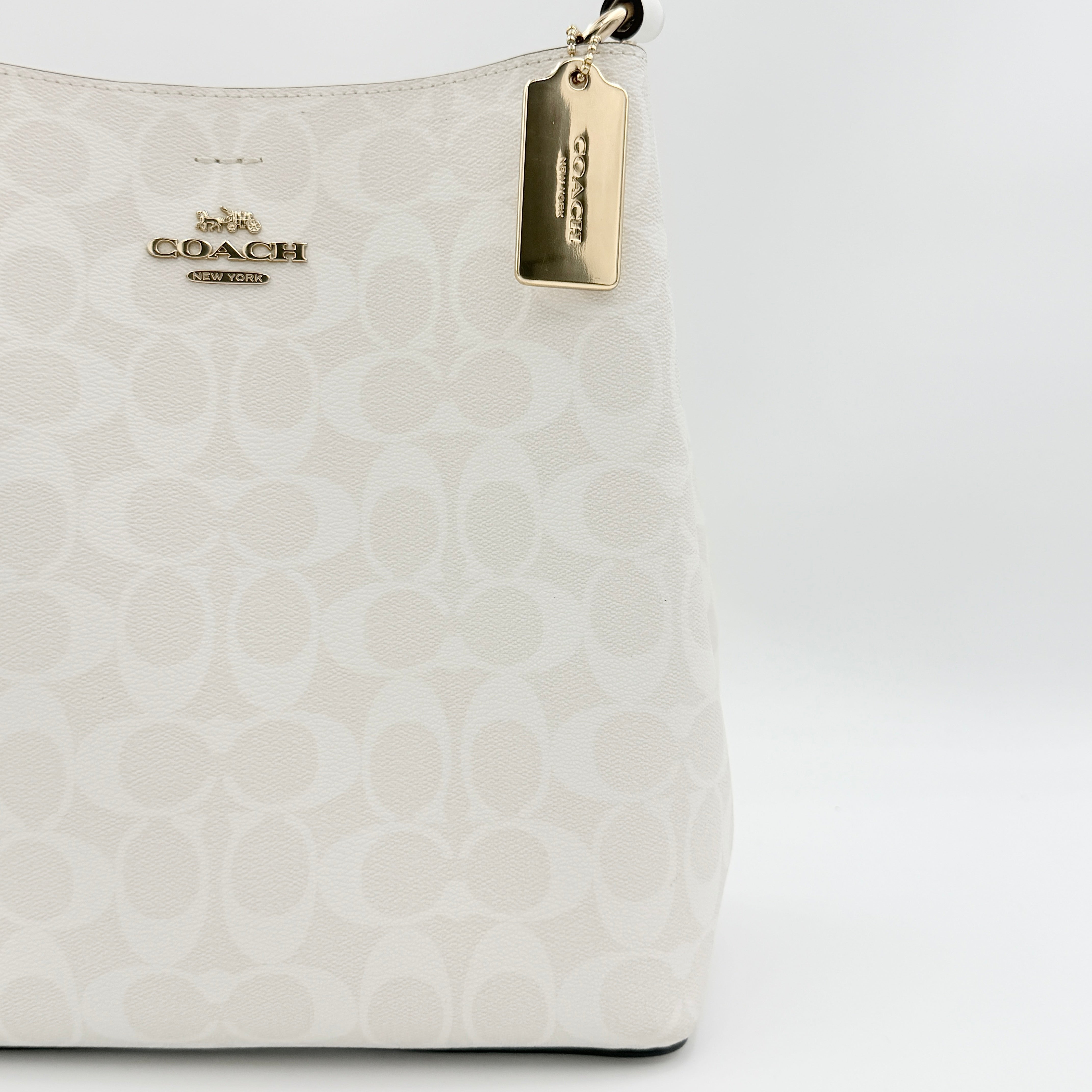 Coach Signature Town Bucket Shoulder Bag in white monogram canvas, shown with detachable strap and gold-tone hardware.