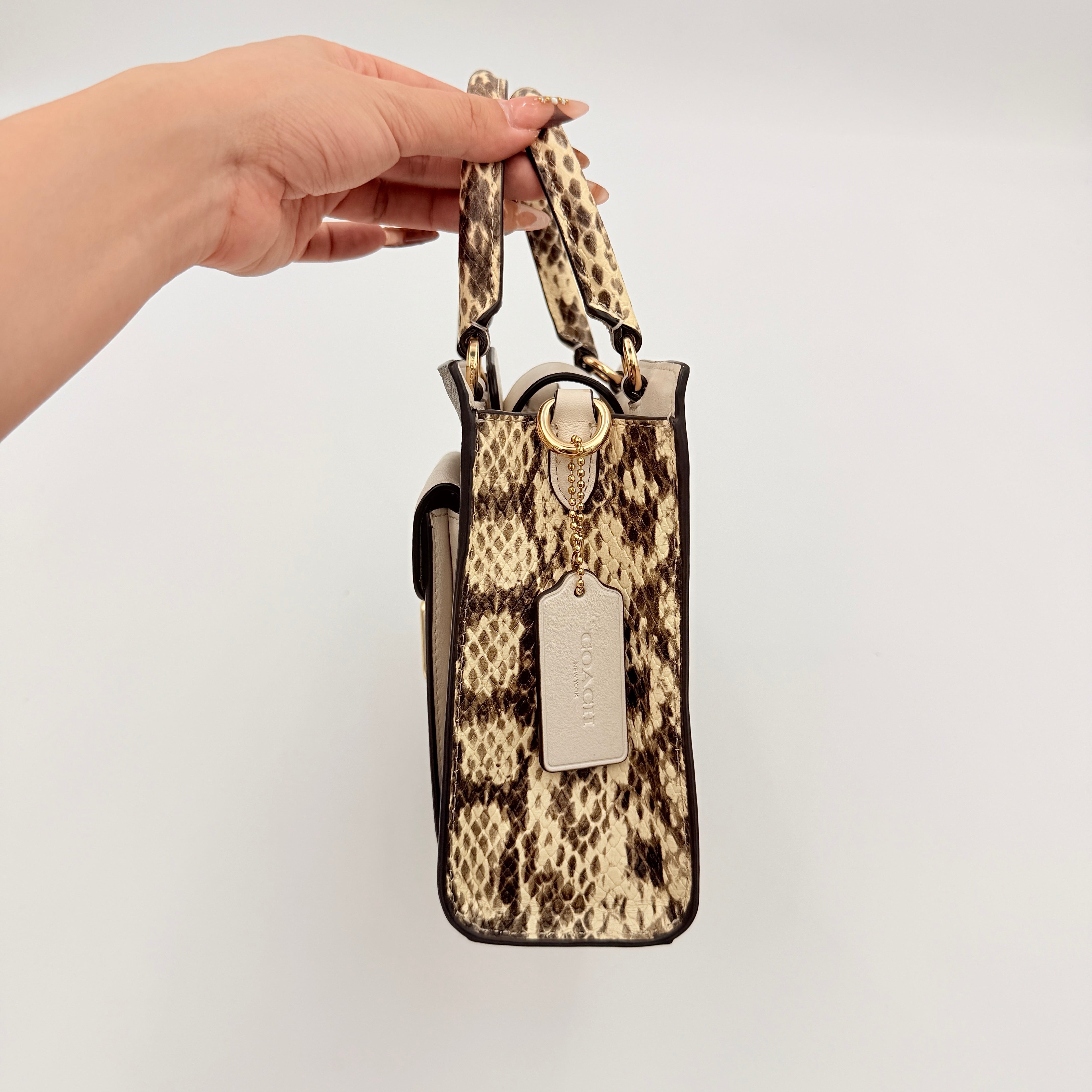 Coach Mini Pepper HandBag in beige canvas with white leather and snakeskin-effect handle, styled with detachable crossbody strap.