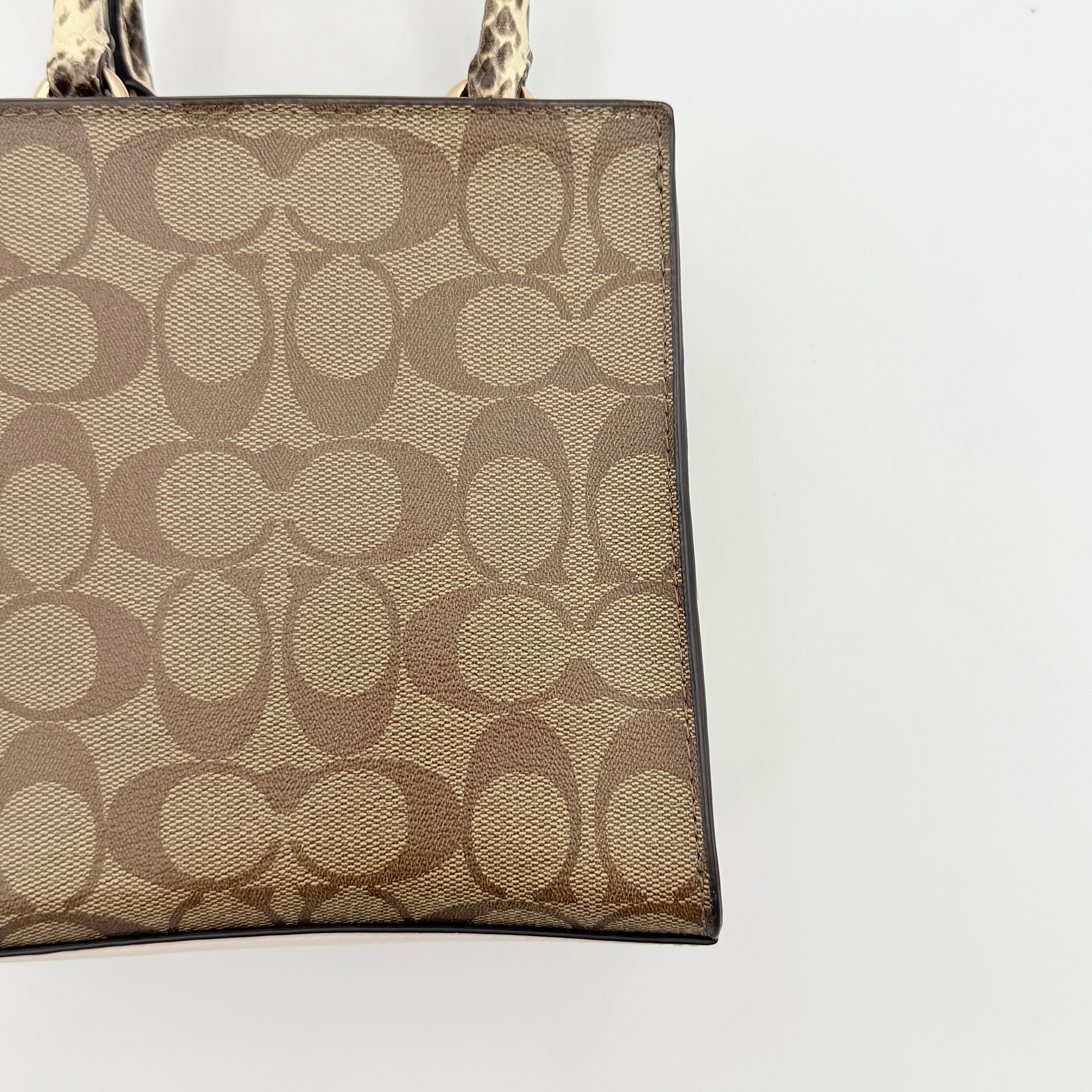 Coach Mini Pepper HandBag in beige canvas with white leather and snakeskin-effect handle, styled with detachable crossbody strap.