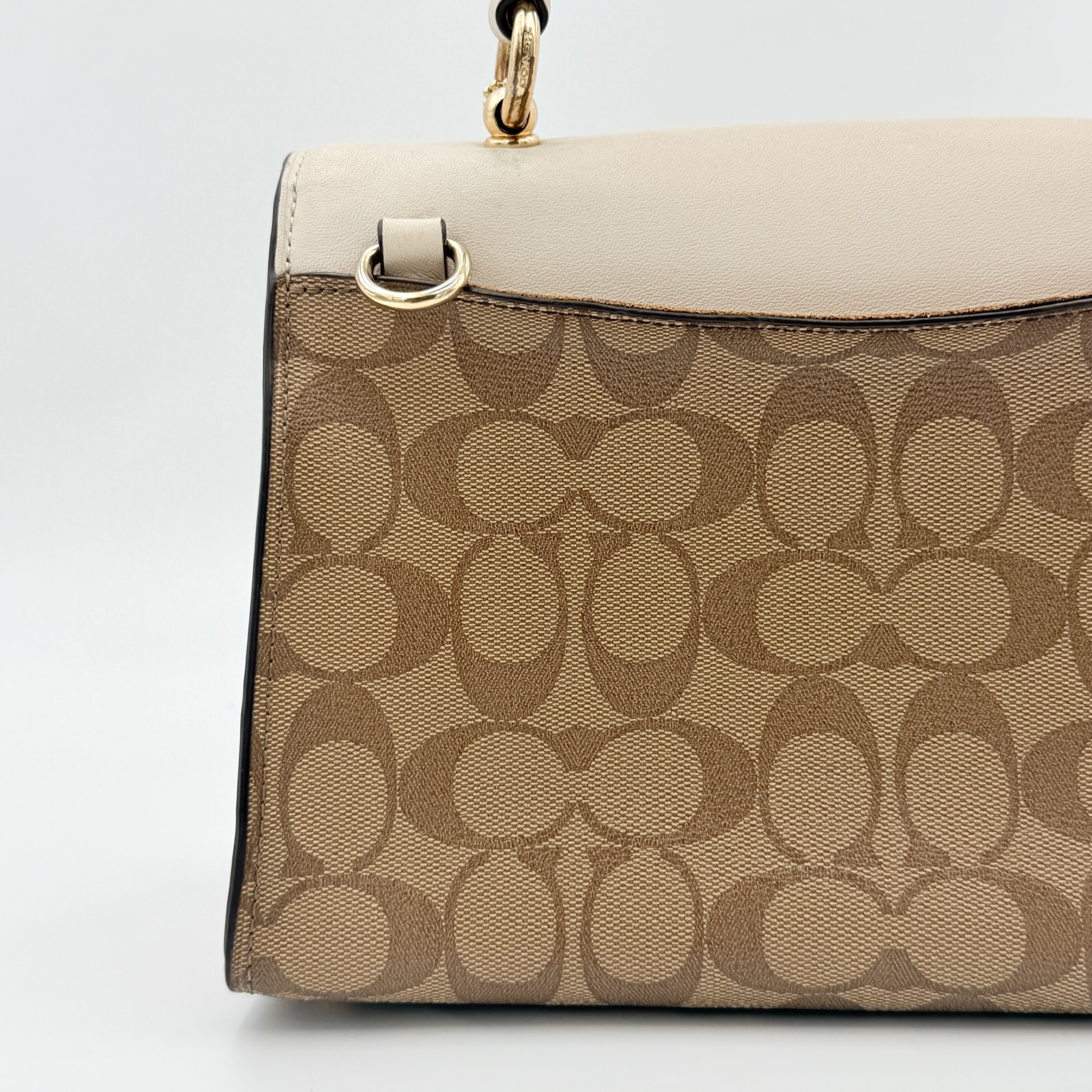 Coach Signature Tilly Top Handle Bag in beige and white with gold-tone hardware and detachable strap, displayed against a clean background.