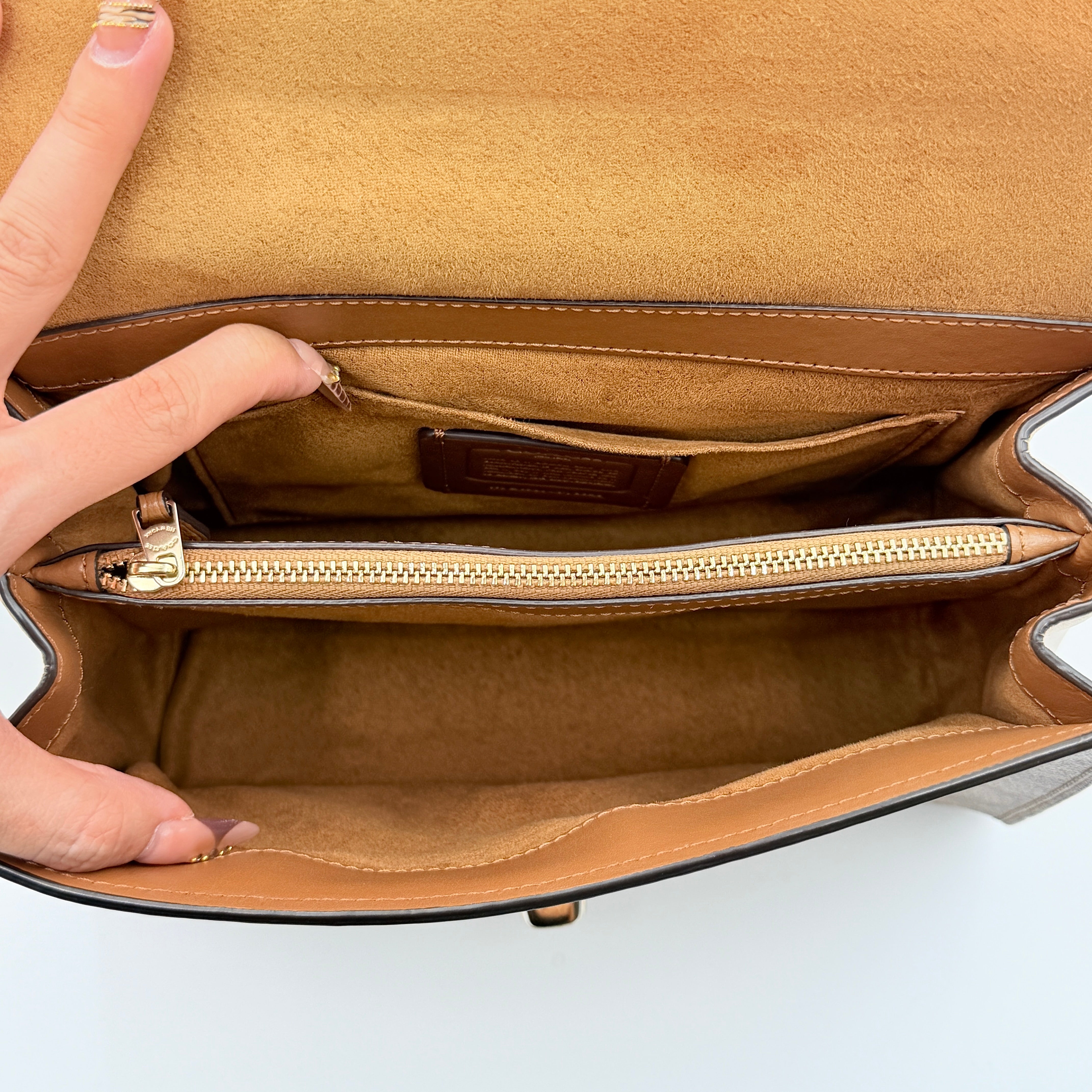 Coach Signature Tilly Top Handle Bag in beige and white with gold-tone hardware and detachable strap, displayed against a clean background.