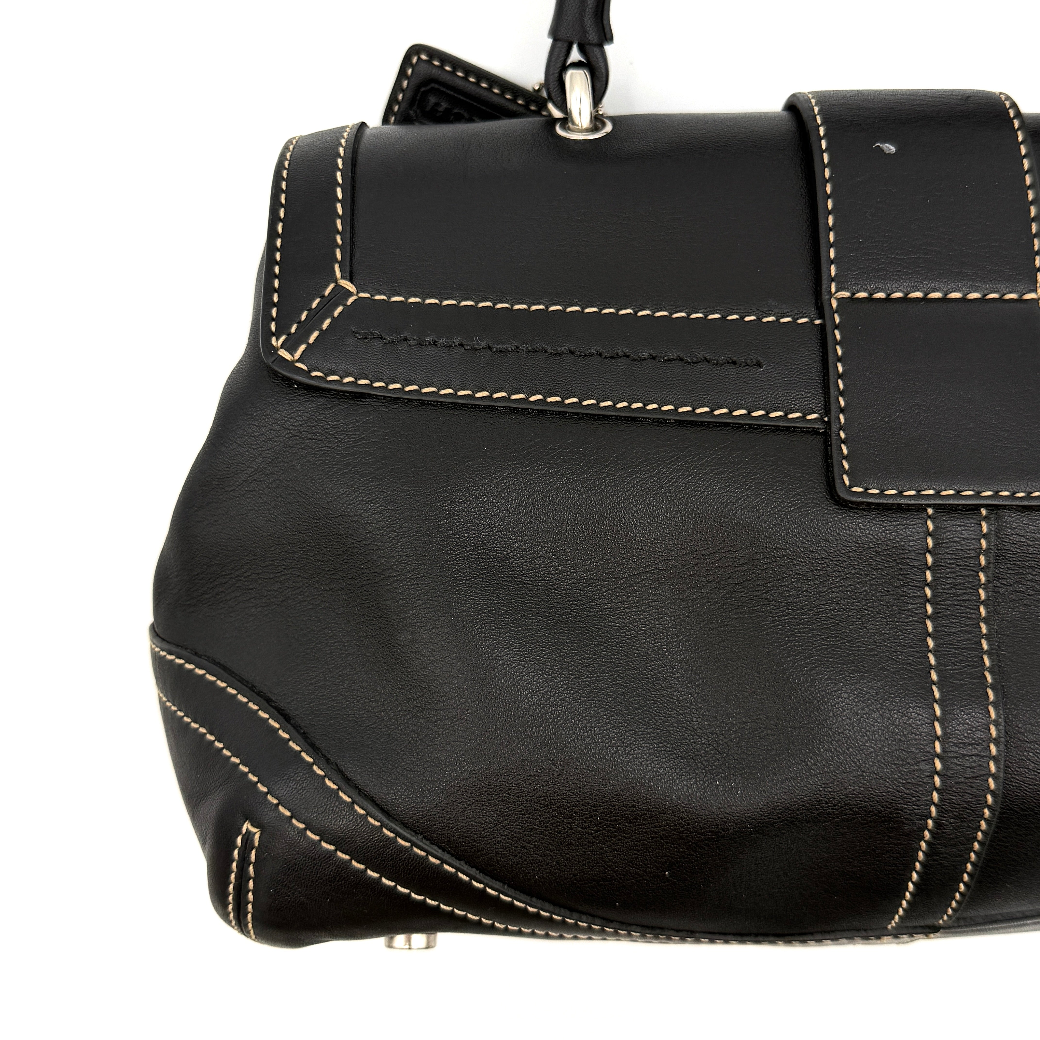 Coach Soho Buckle Top Handle Bag in black leather with contrast stitching and silver buckle, presented against a white background.
