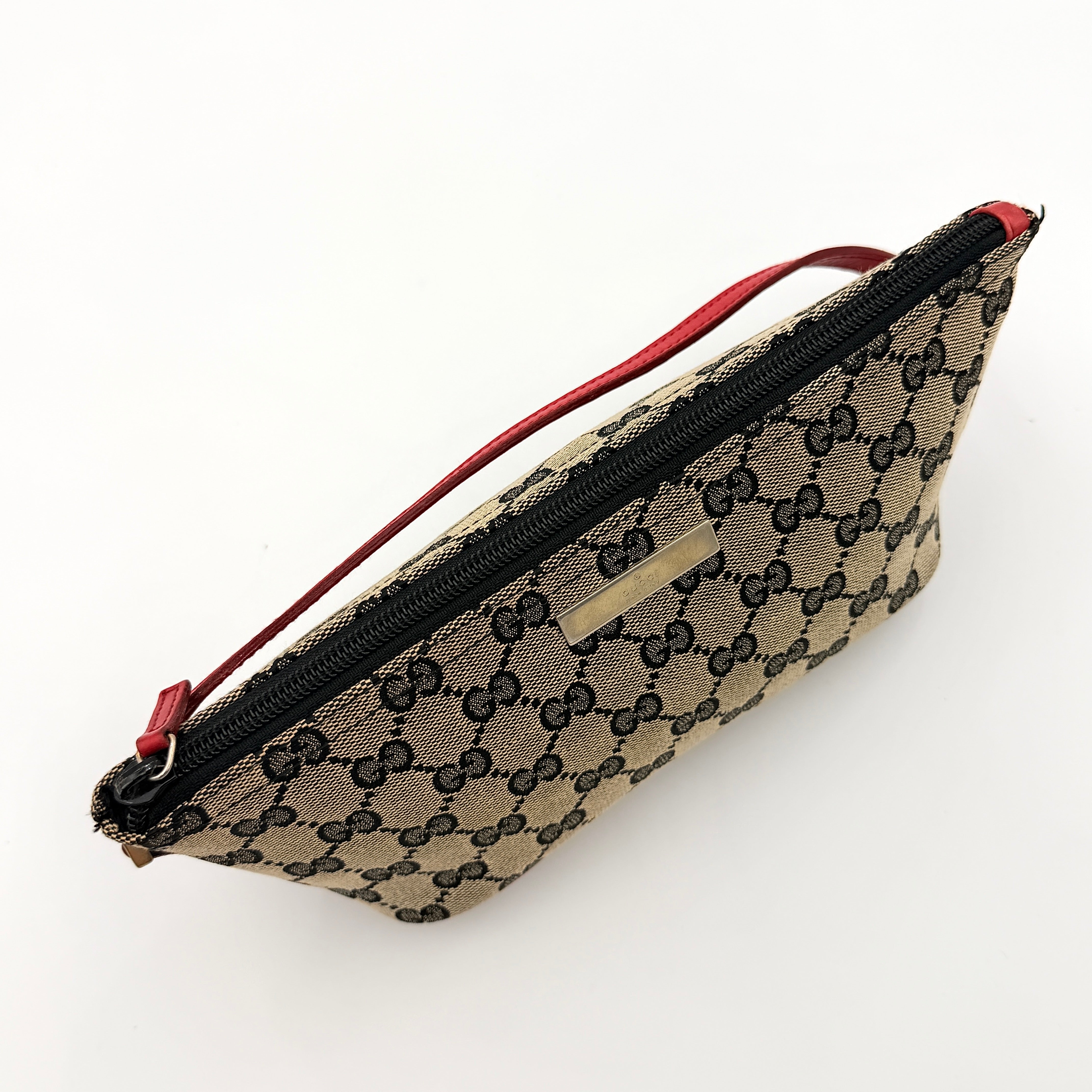 Gucci GG Monogram Pochette Boat Shoulder Bag in grey canvas with red leather trim and gold plaque, shown against a plain background.