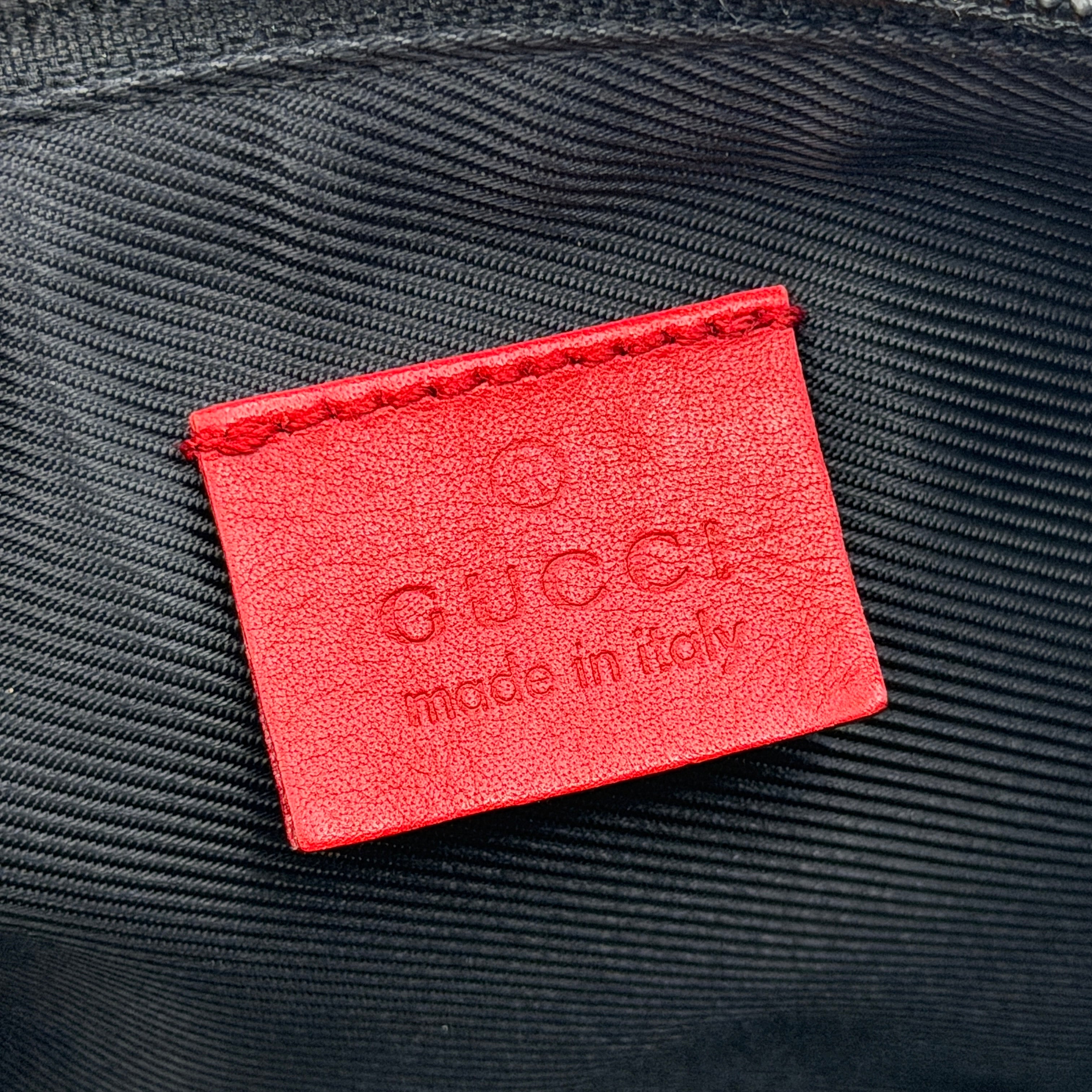 Gucci GG Monogram Pochette Boat Shoulder Bag in grey canvas with red leather trim and gold plaque, shown against a plain background.