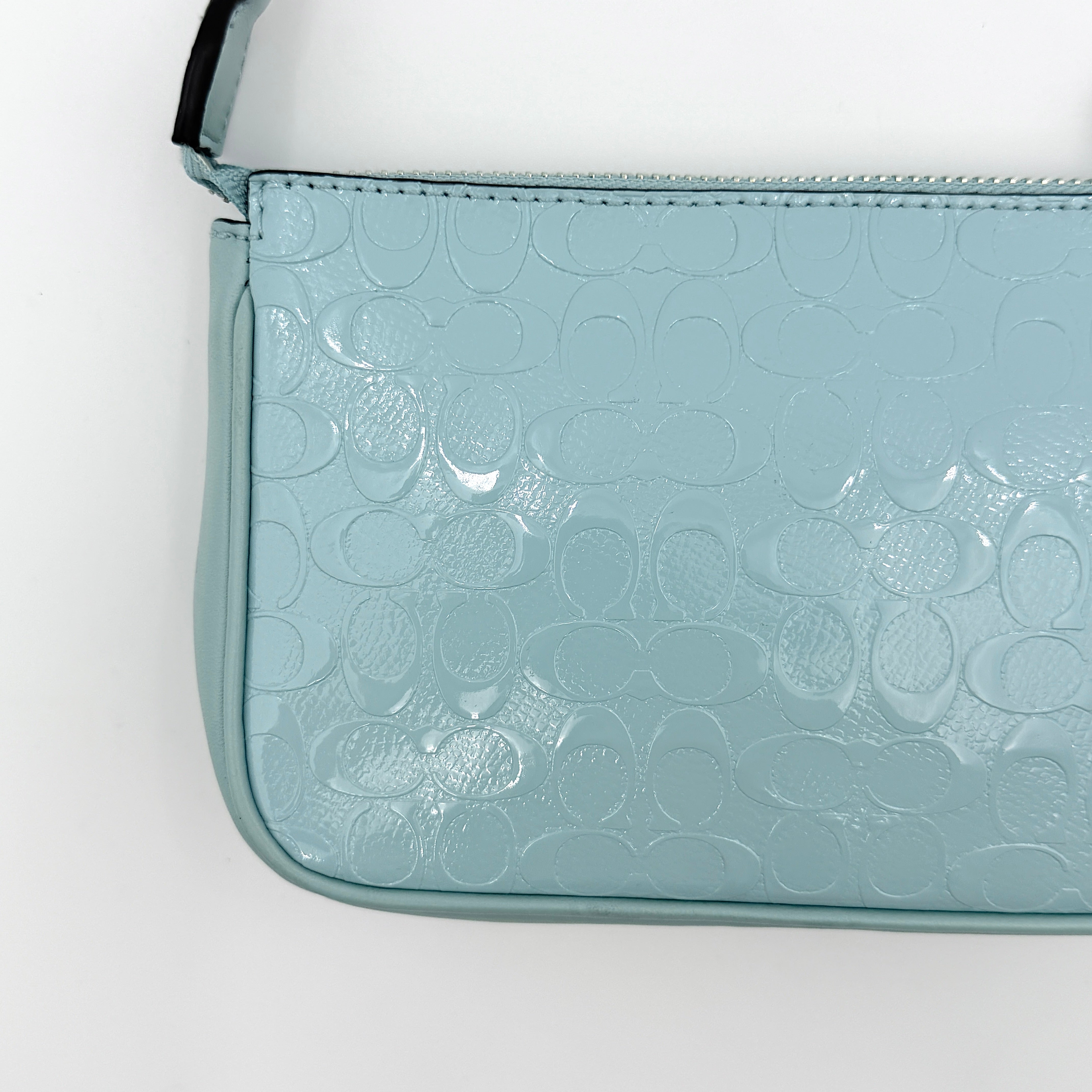 Coach Nolita 19 small shoulder bag in light blue embossed patent leather with silver-tone chain strap shown against a white background.