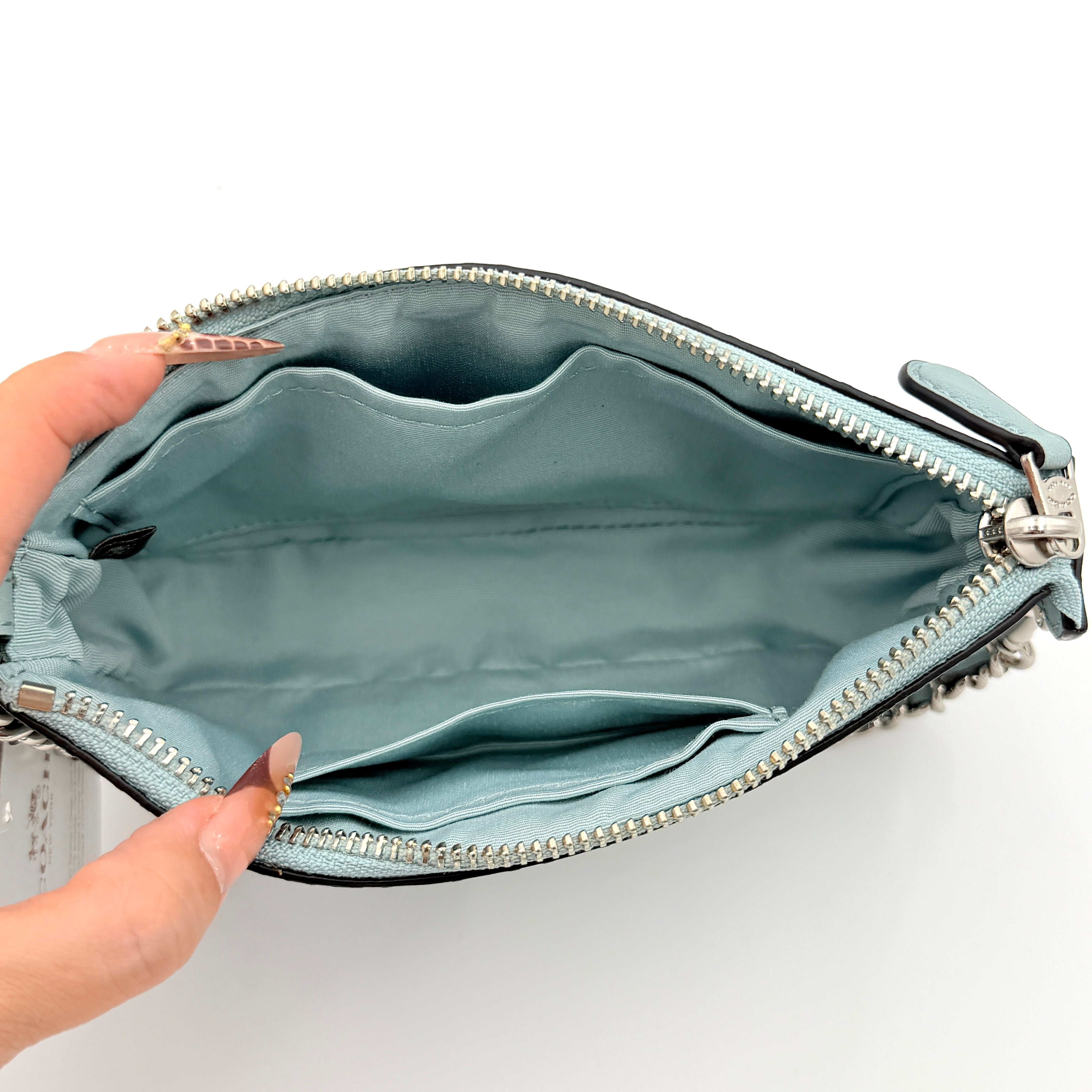 Coach Nolita 19 small shoulder bag in light blue embossed patent leather with silver-tone chain strap shown against a white background.