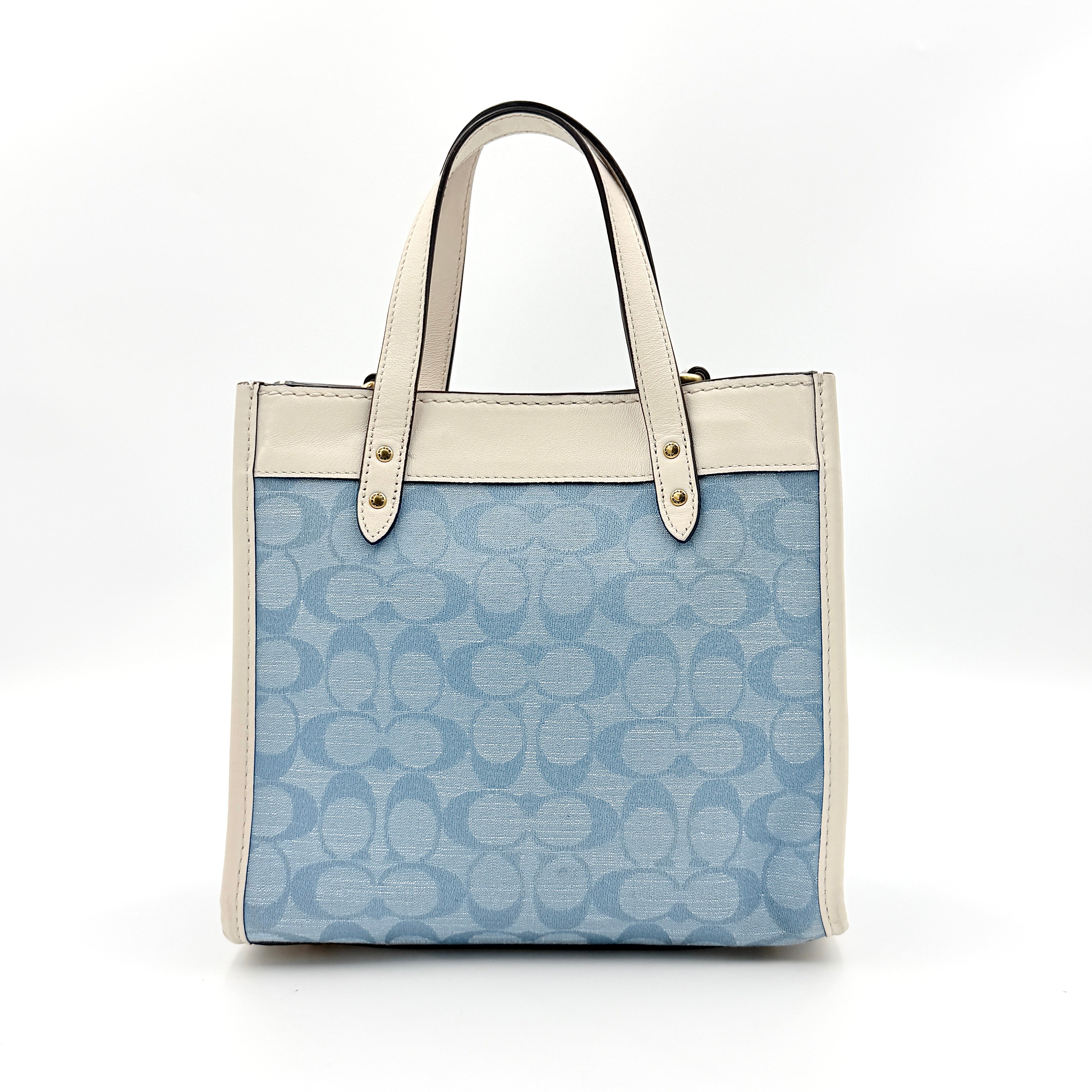 Coach Field Tote 22 in blue signature jacquard with white leather trim and detachable strap, styled for versatile wear.