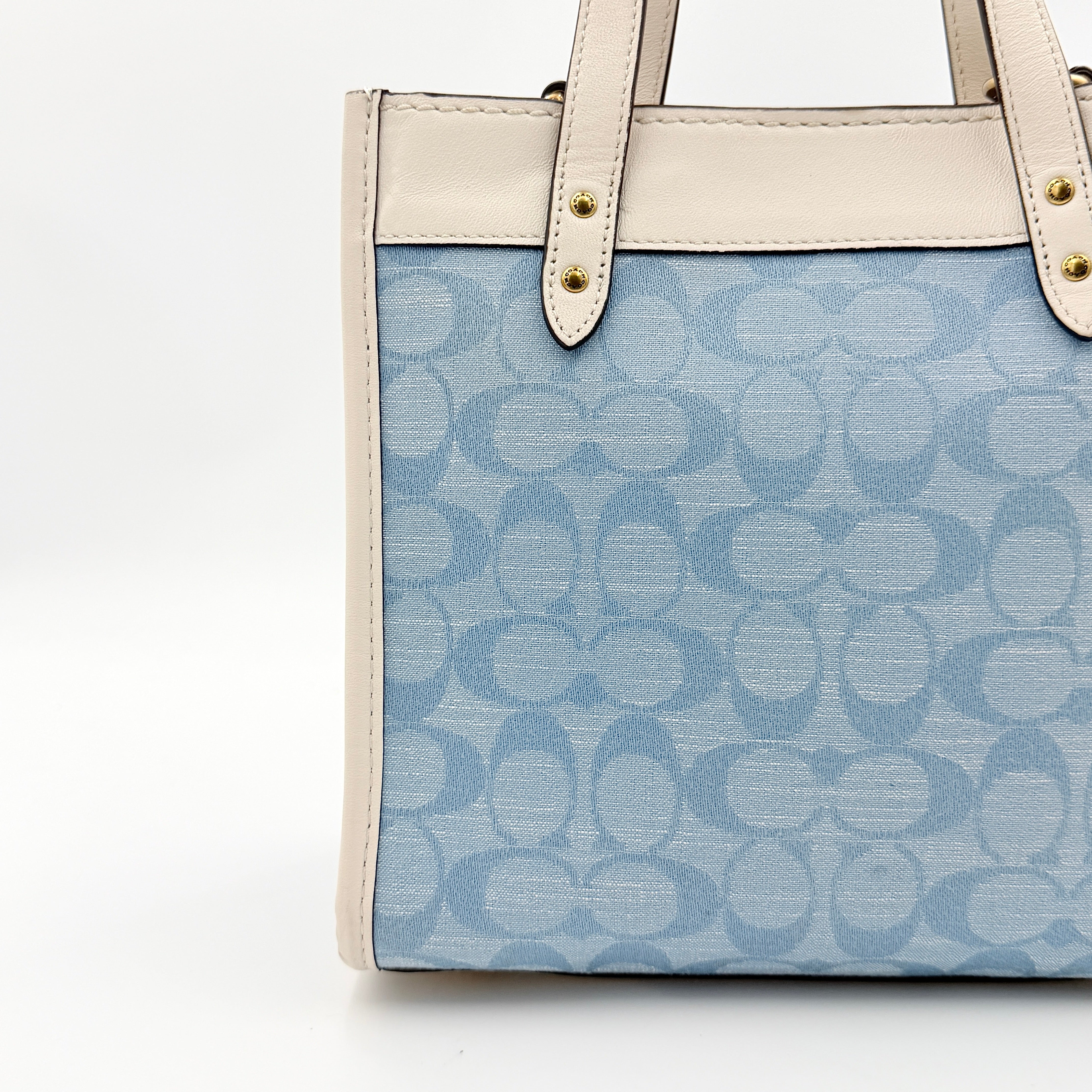 Coach Field Tote 22 in blue signature jacquard with white leather trim and detachable strap, styled for versatile wear.