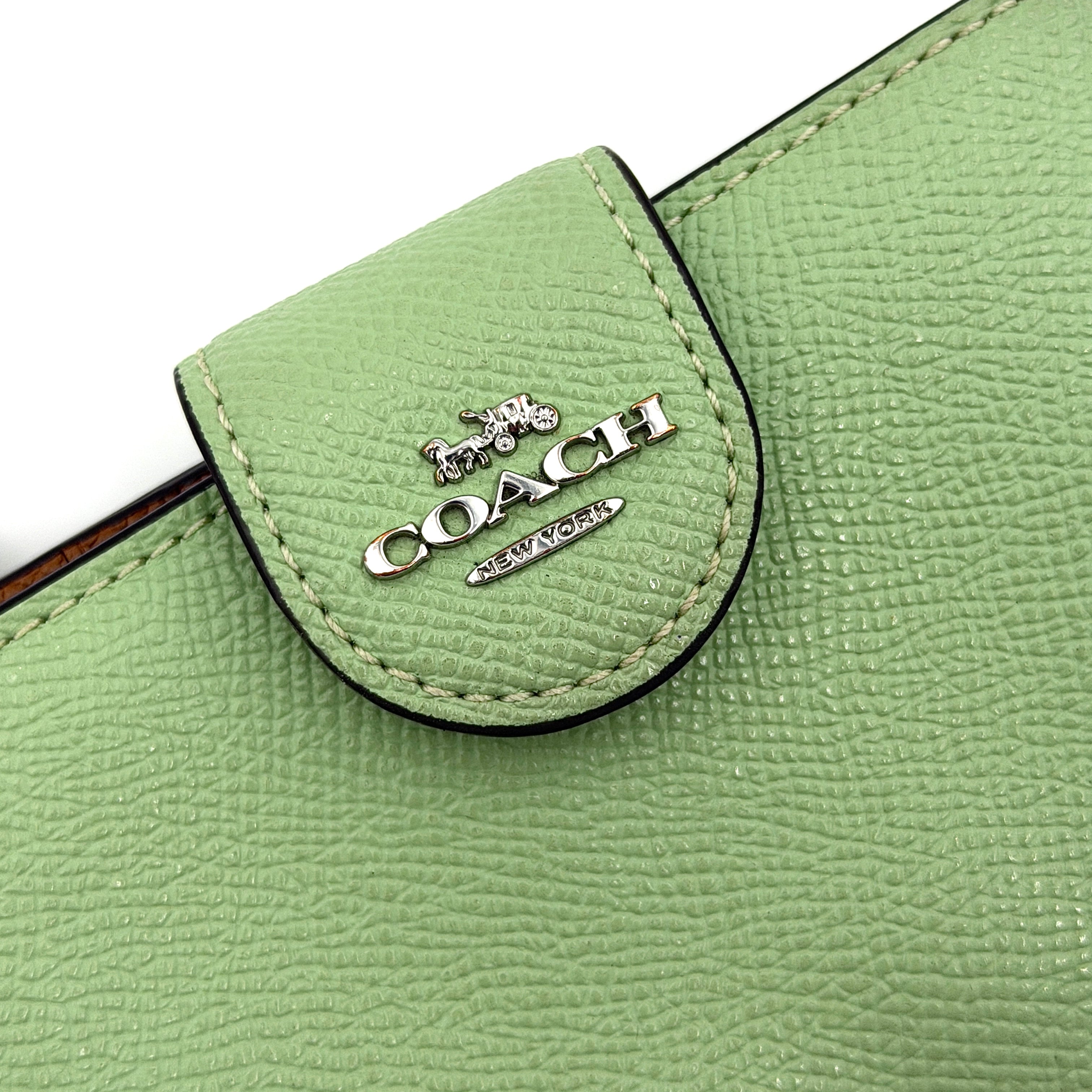 Coach Medium Corner Zip Wallet in fresh green pebbled leather with silver logo hardware and organised tan interior.
