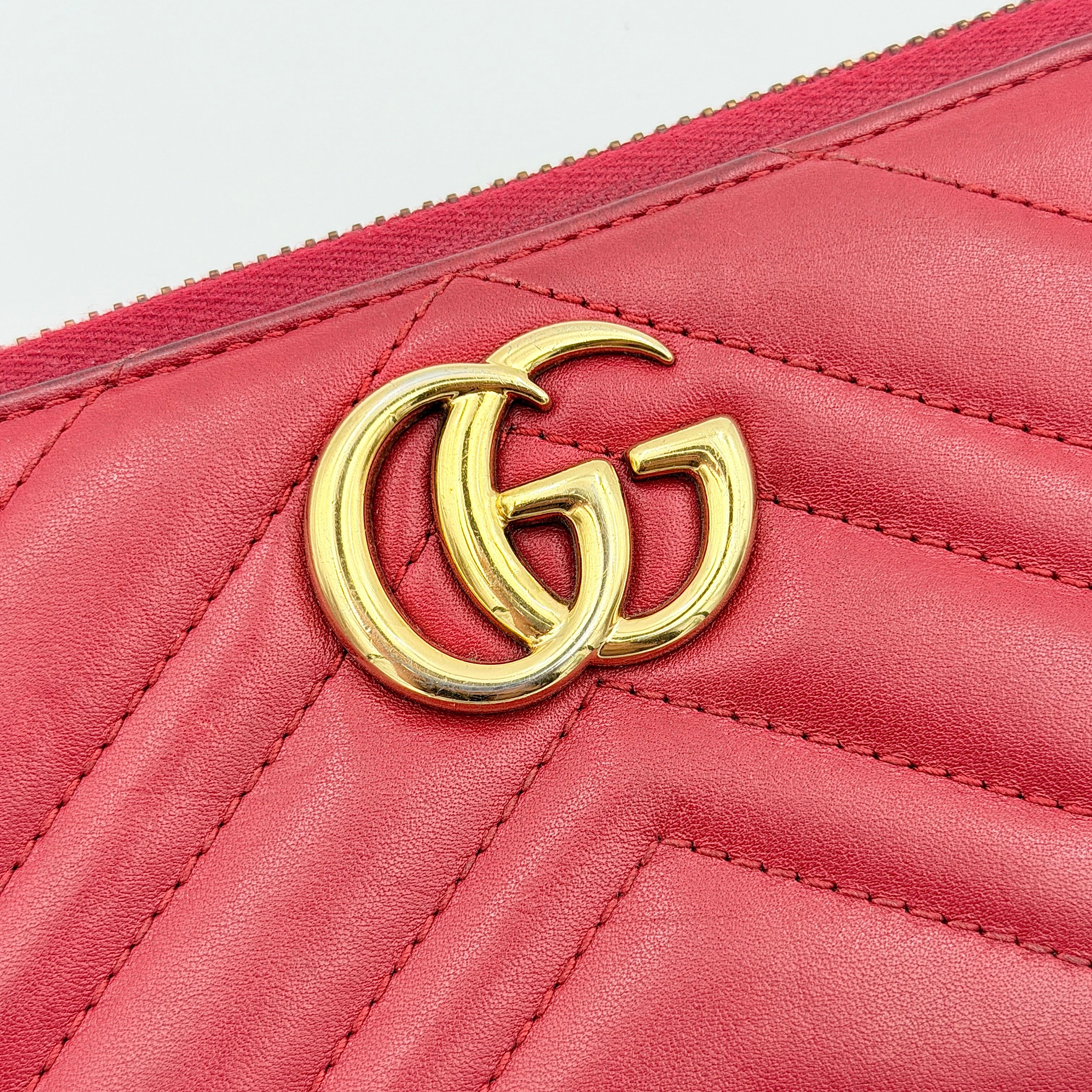 Gucci GG Marmont quilted long wallet in red leather with gold hardware displayed flat against a white background.