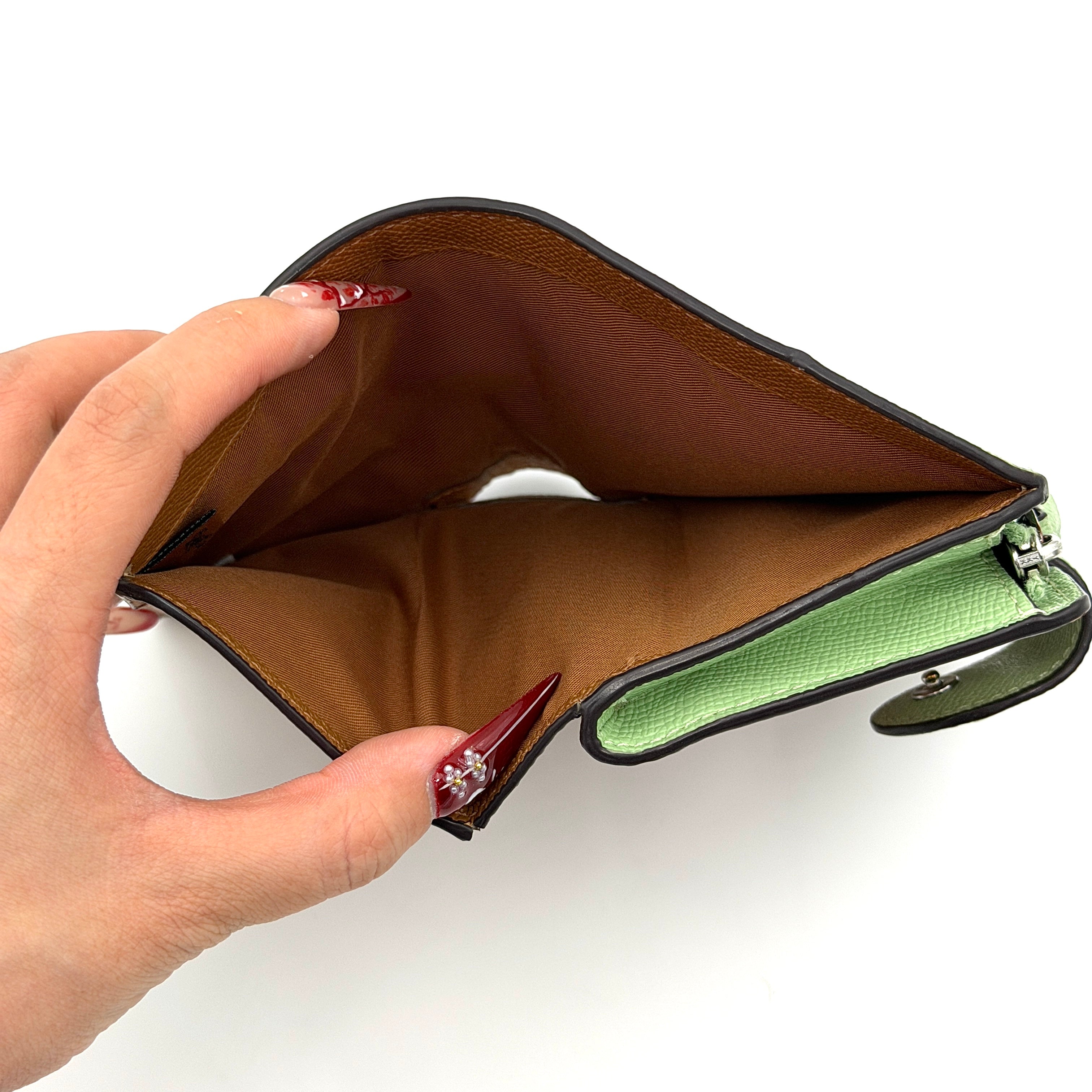 Coach Medium Corner Zip Wallet in fresh green pebbled leather with silver logo hardware and organised tan interior.