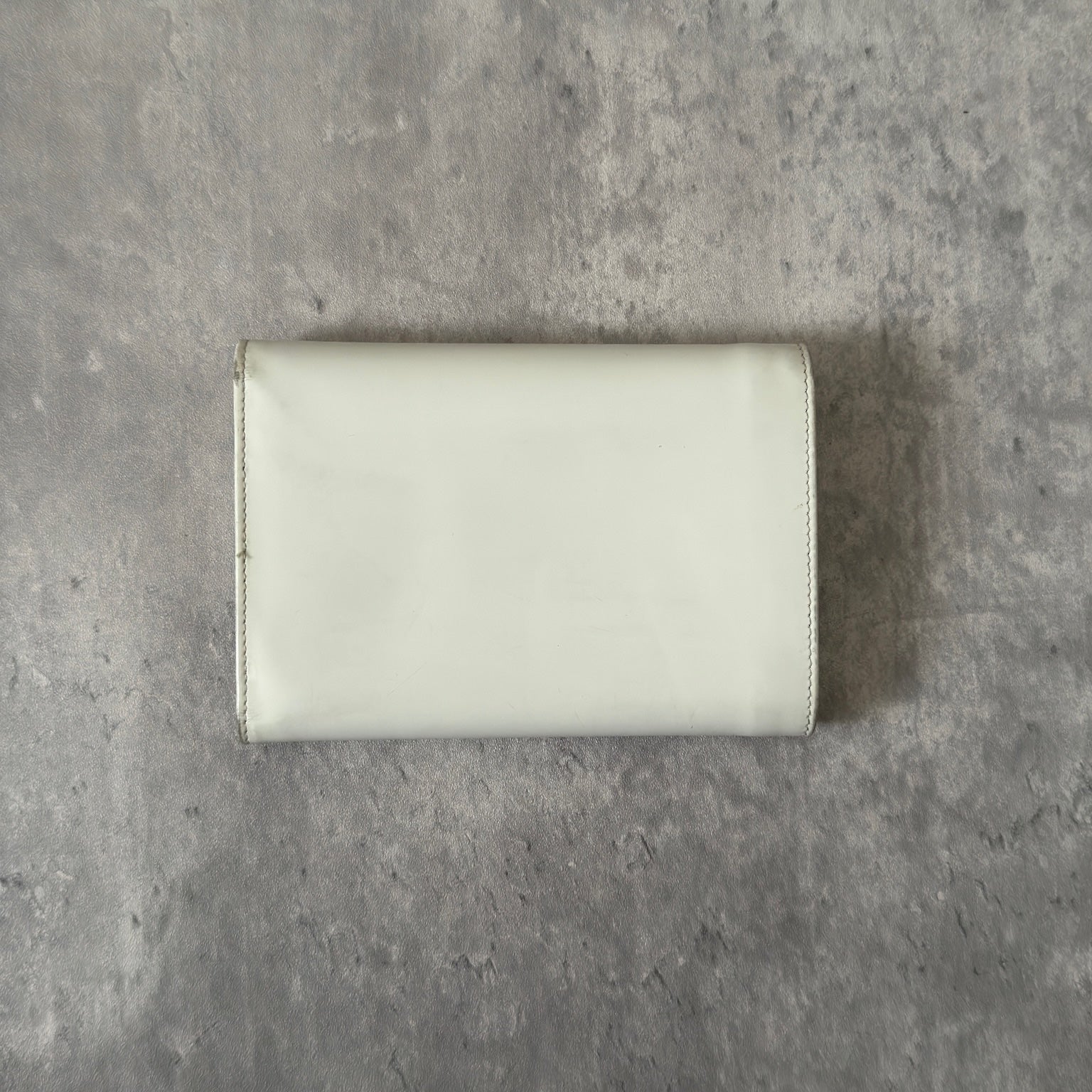 Prada City Calf Leather Compact Wallet in off-white with flap closure and embossed logo detail, showcasing a sophisticated, minimalist design.