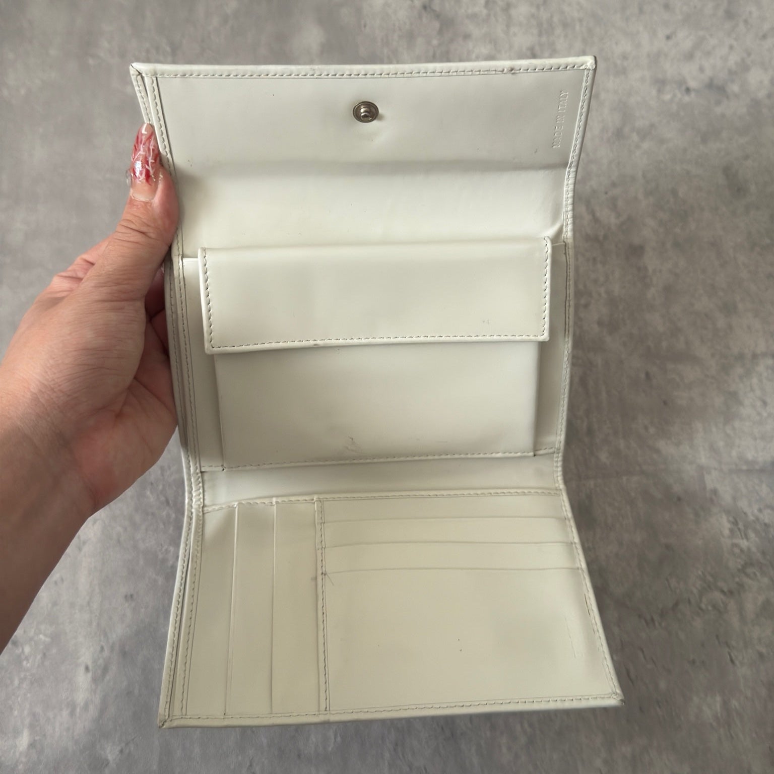 Prada City Calf Leather Compact Wallet in off-white with flap closure and embossed logo detail, showcasing a sophisticated, minimalist design.