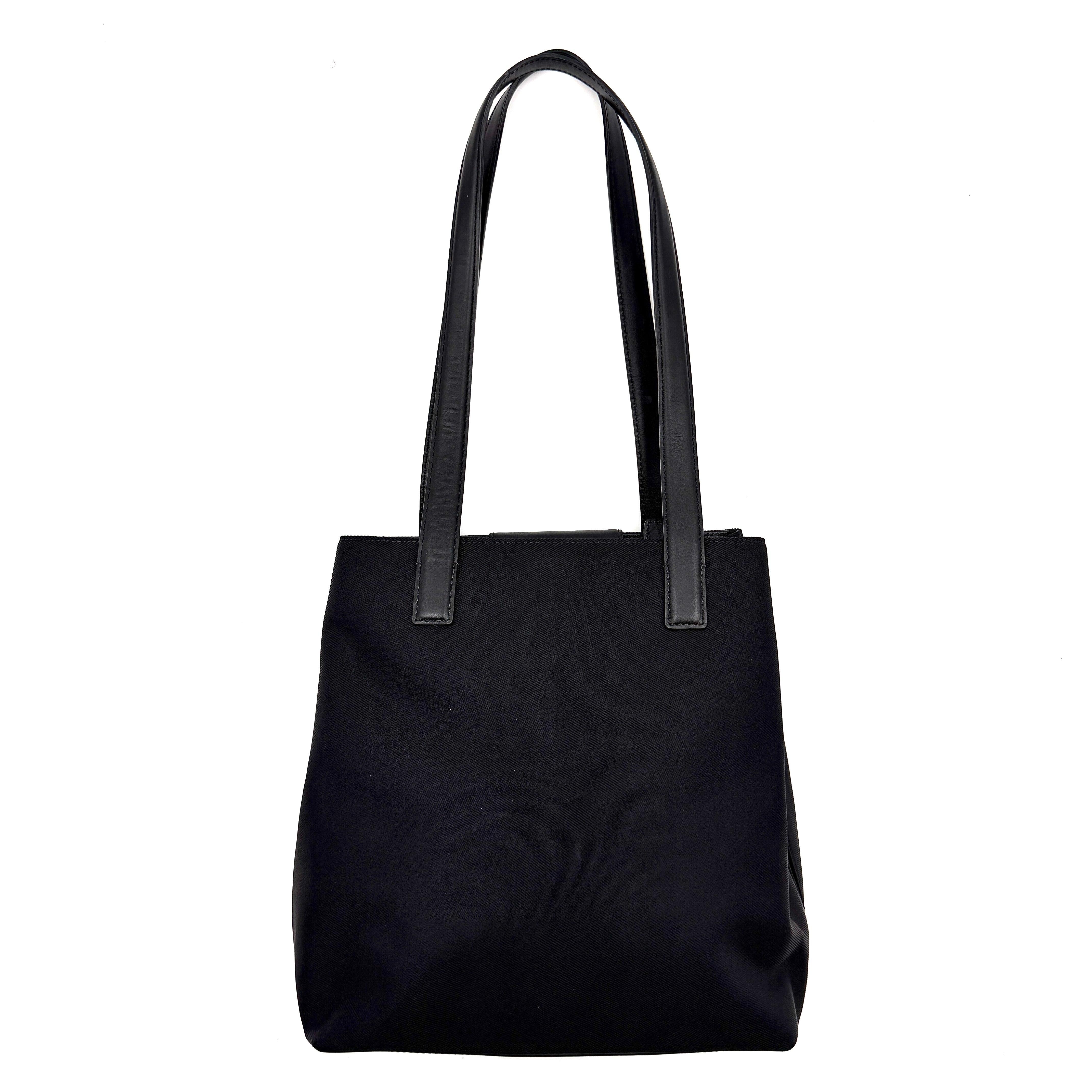 Coach Mercer Nylon Tote Bag in black with structured silhouette, leather handles, and subtle silver logo plaque at the base.