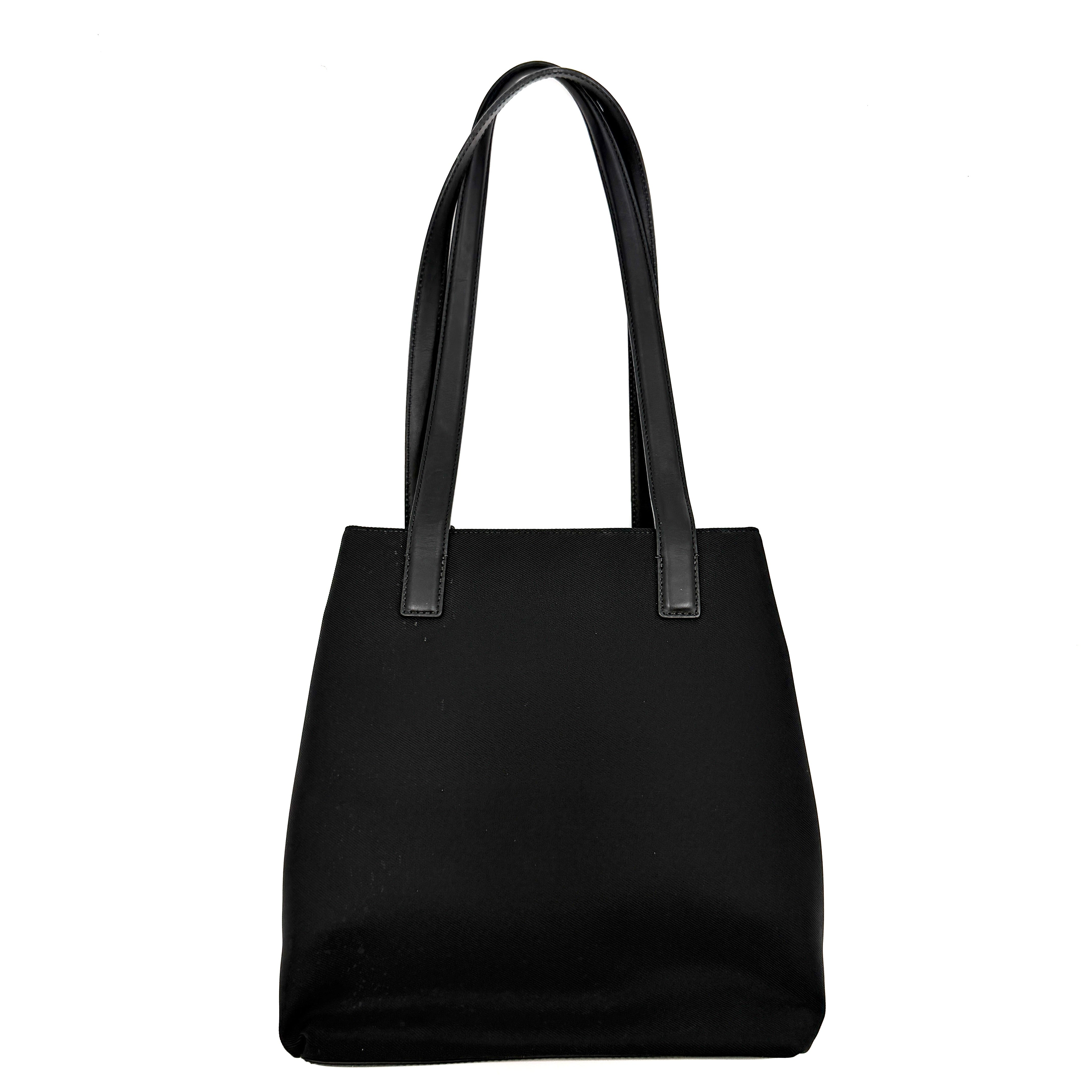 Coach Mercer Nylon Tote Bag in black with structured silhouette, leather handles, and subtle silver logo plaque at the base.