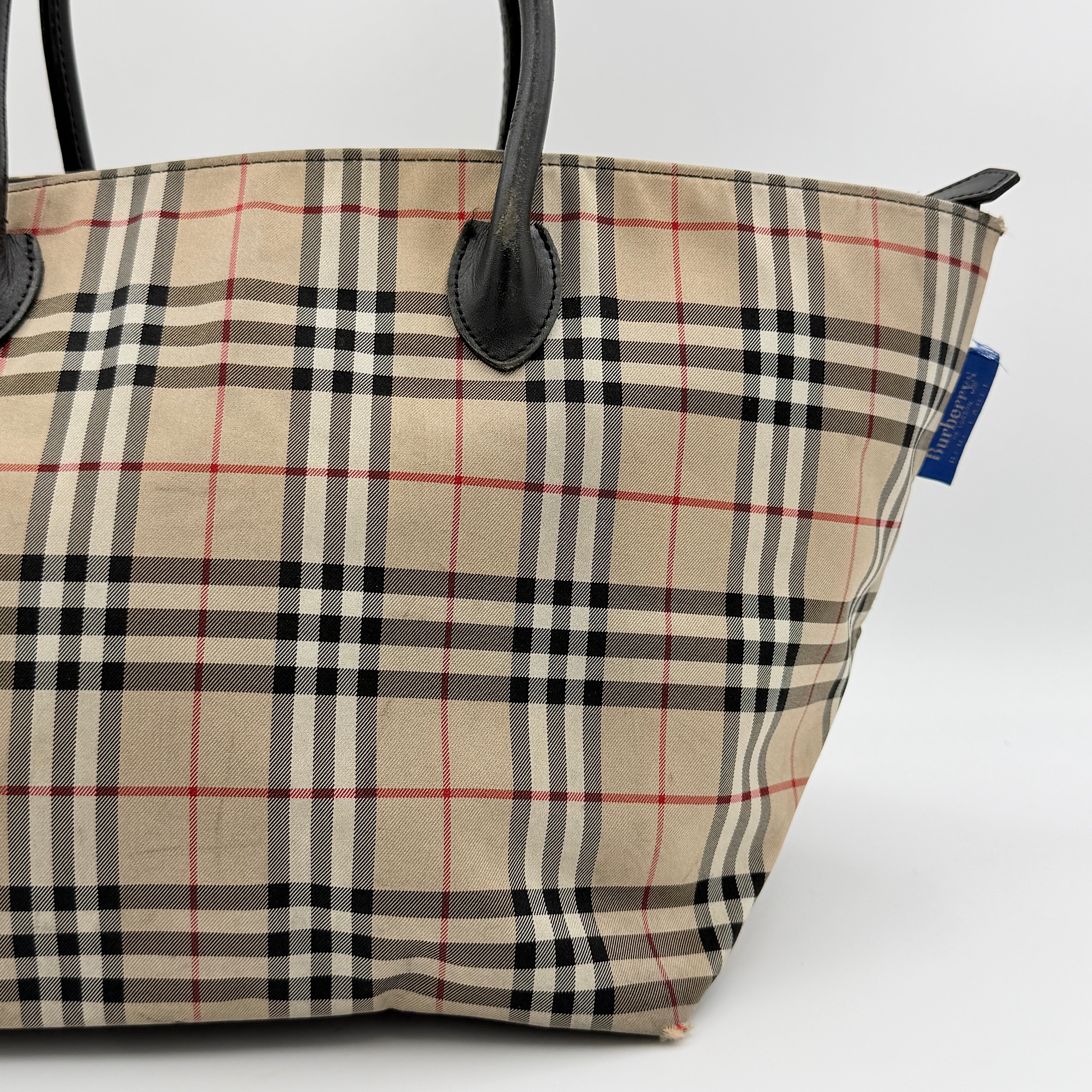 Burberry Nova Check shoulder bag in beige and black with black leather handles and zip closure.