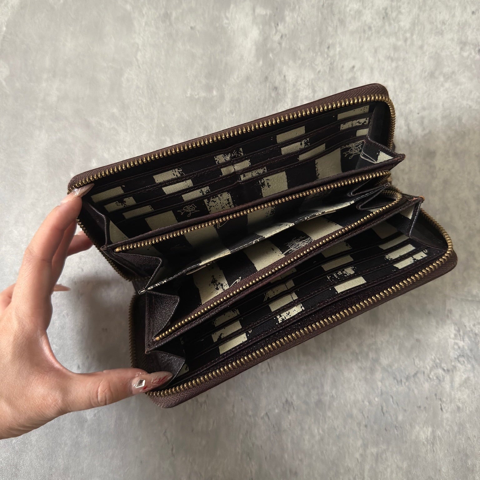 Vivienne Westwood Seditionaries Wallet, black leather, featuring the iconic gold-tone Orb emblem and a zip-around closure, interior detailed with brand's signature pattern.