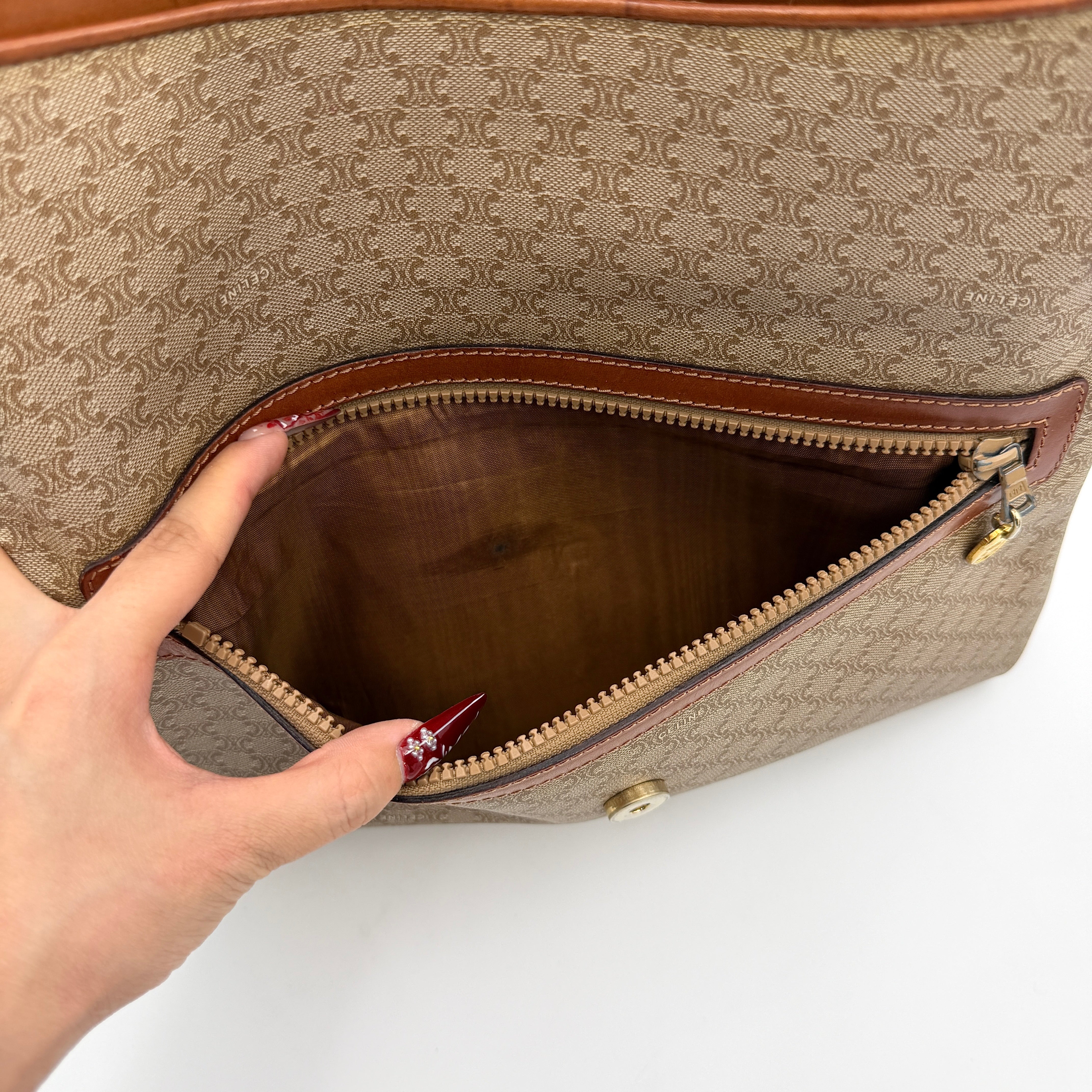 The Celine Macadam Clutch Bag in beige, featuring the iconic monogram canvas and tan leather trim, shown neatly closed with its signature emblem on the flap.