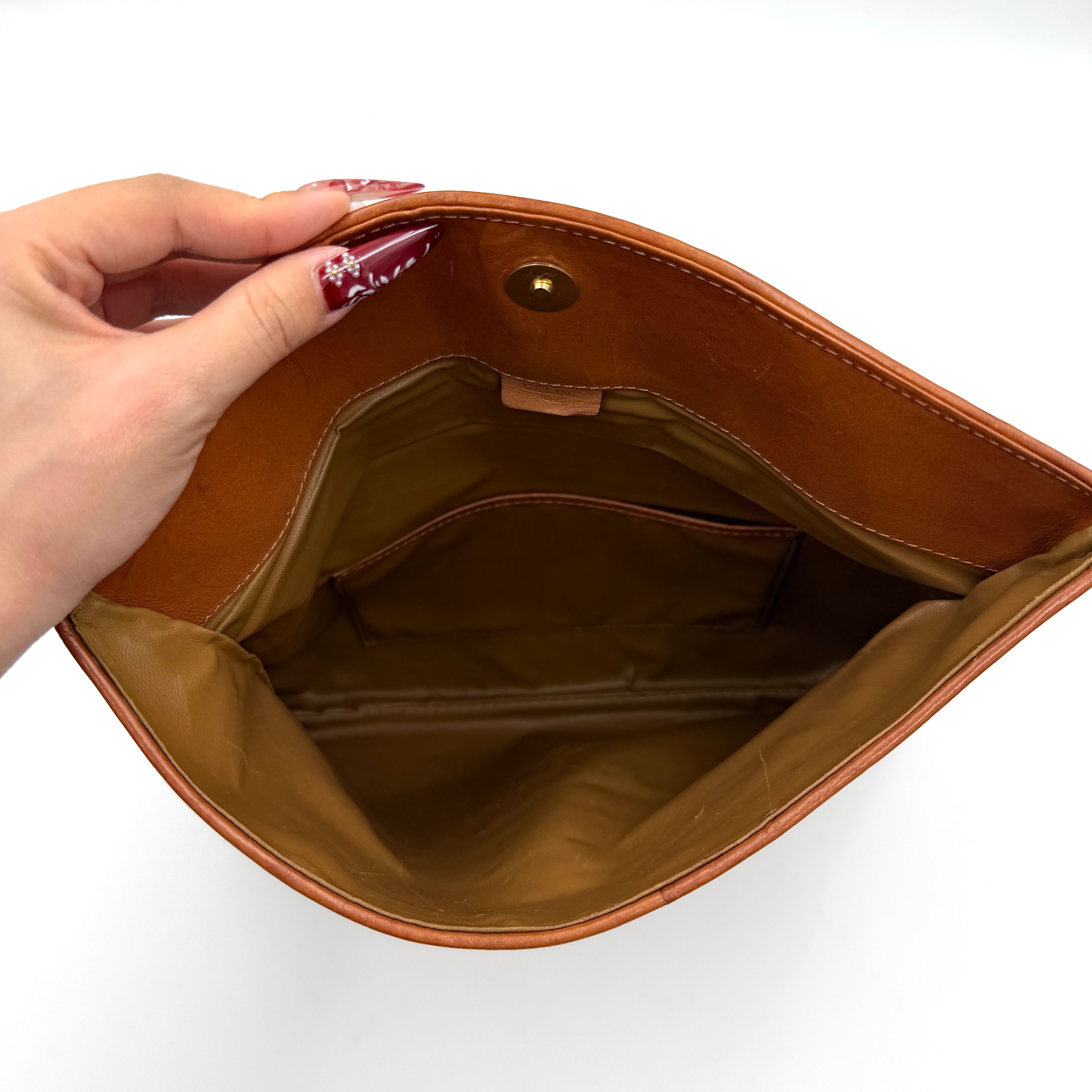 The Celine Macadam Clutch Bag in beige, featuring the iconic monogram canvas and tan leather trim, shown neatly closed with its signature emblem on the flap.
