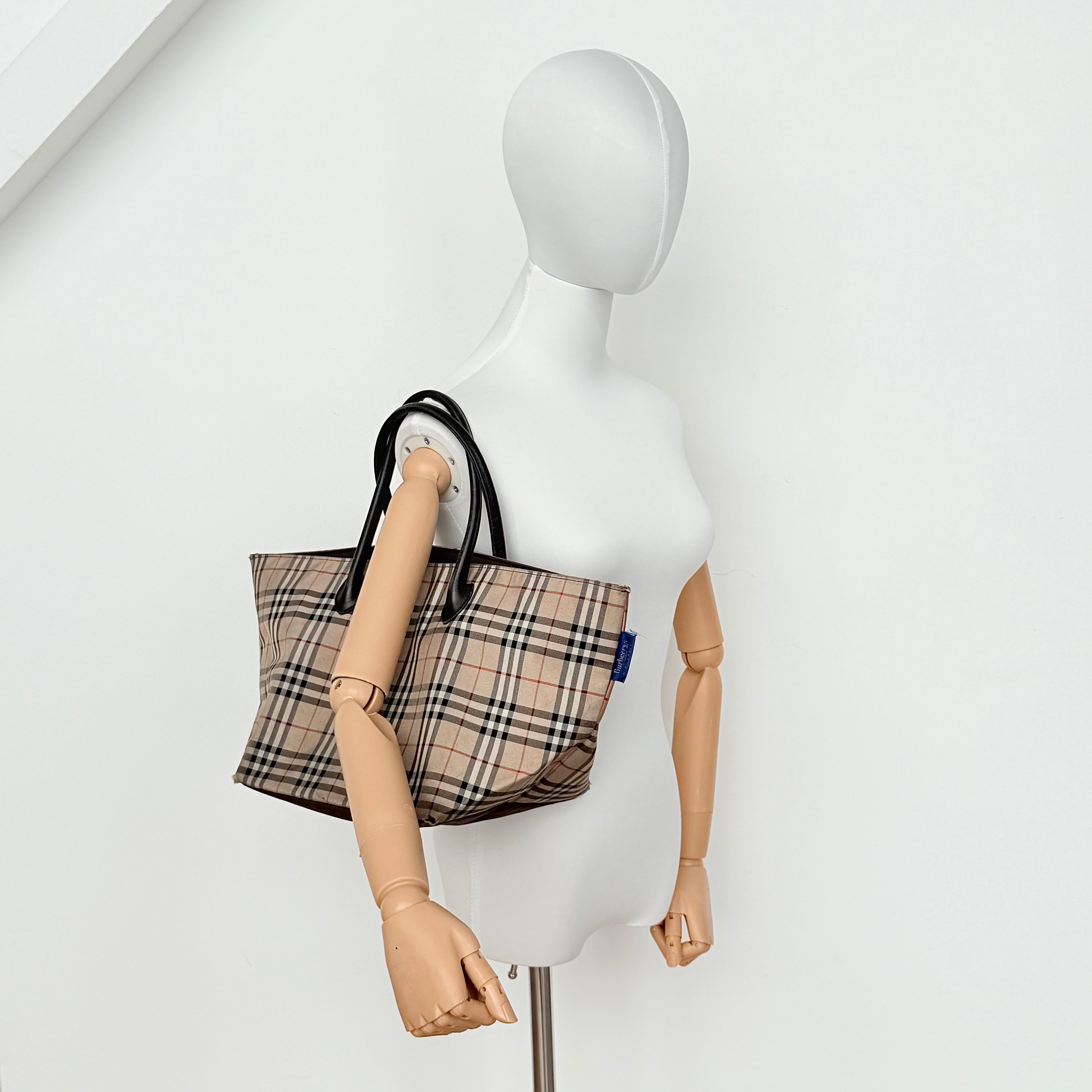 Burberry Nova Check shoulder bag in beige and black with black leather handles and zip closure.